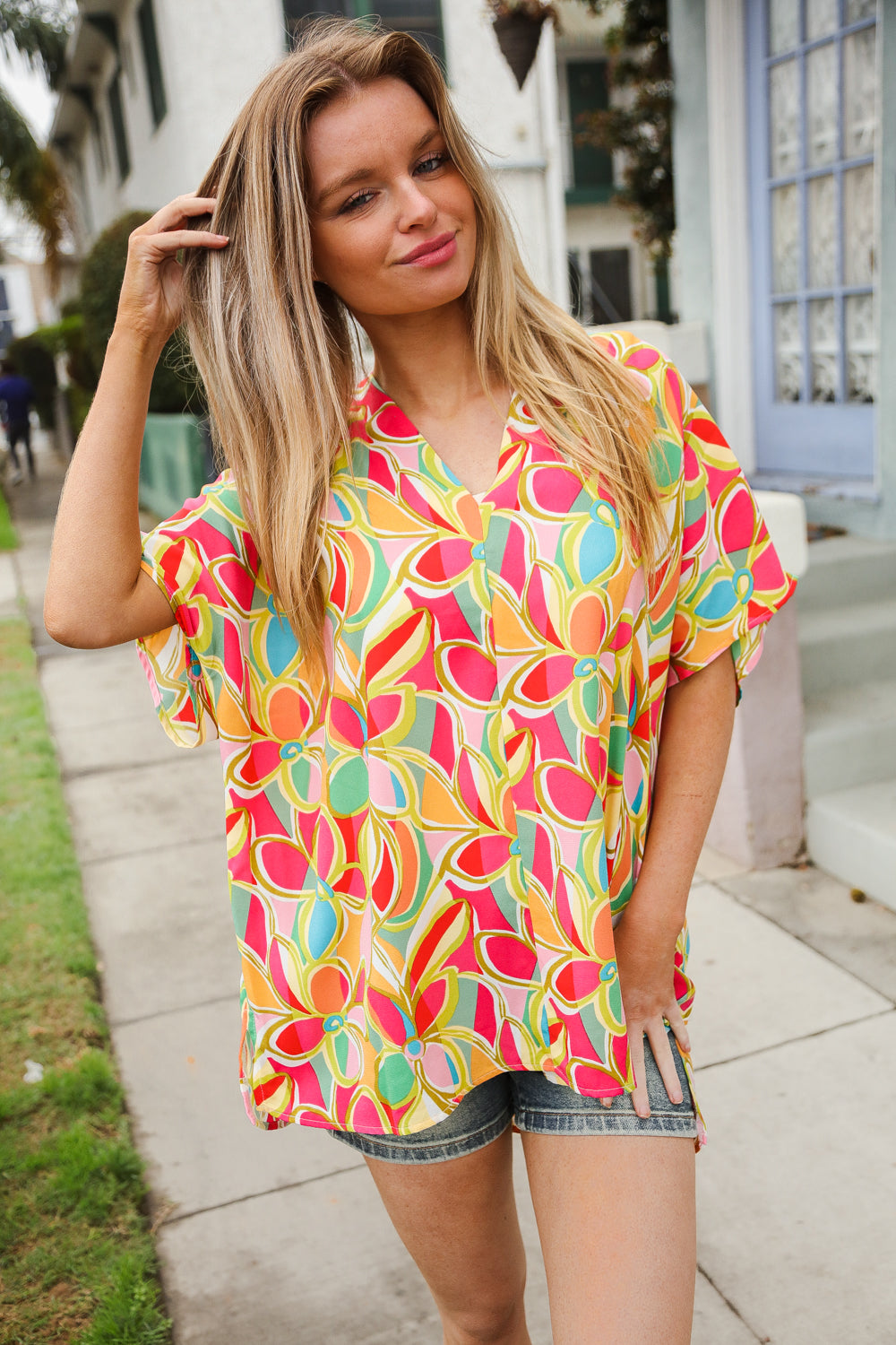 Woman wearing a colorful patterned shirt standing outdoors.