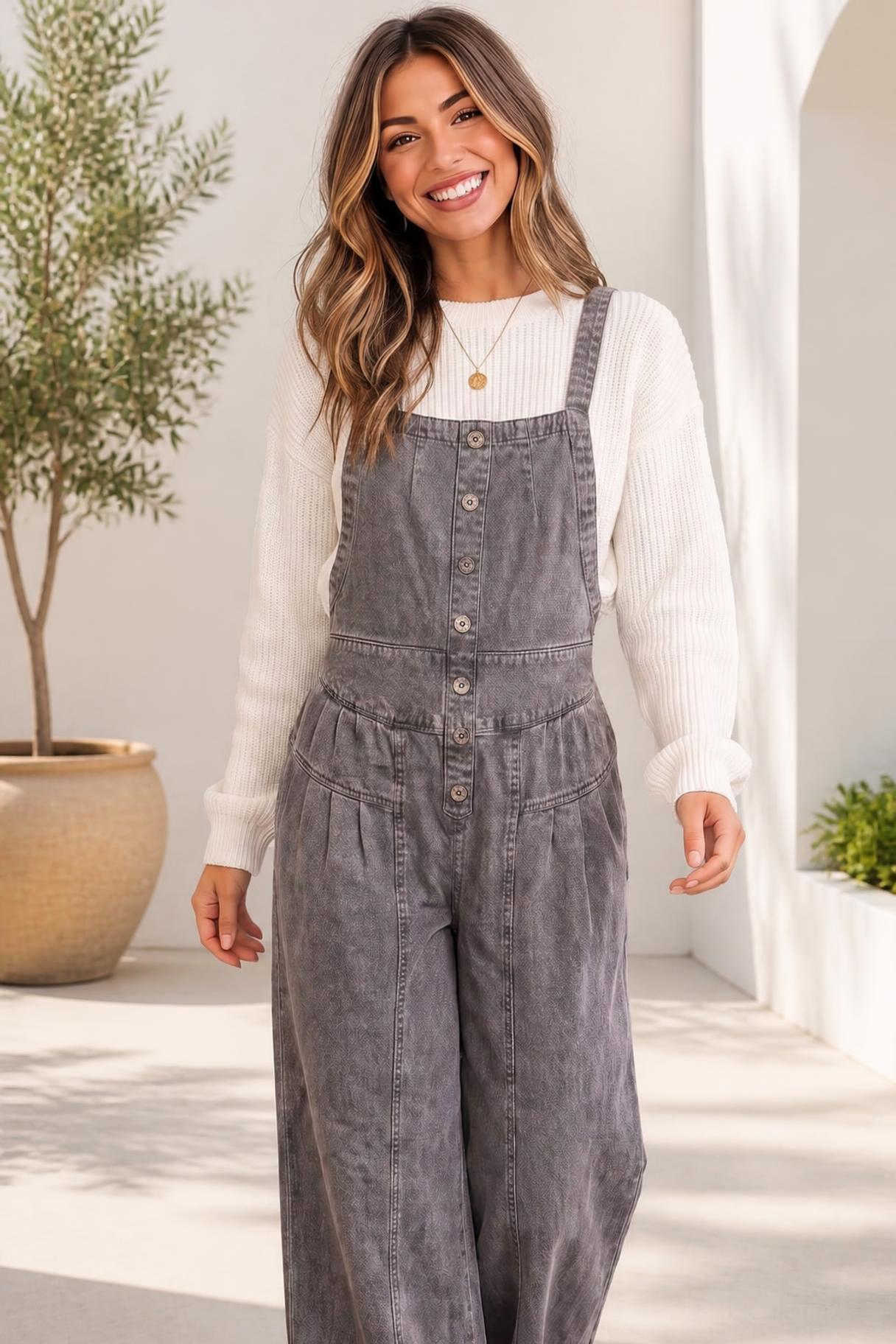 Gray wide leg denim overall with adjustable straps and button-front bib detail.
