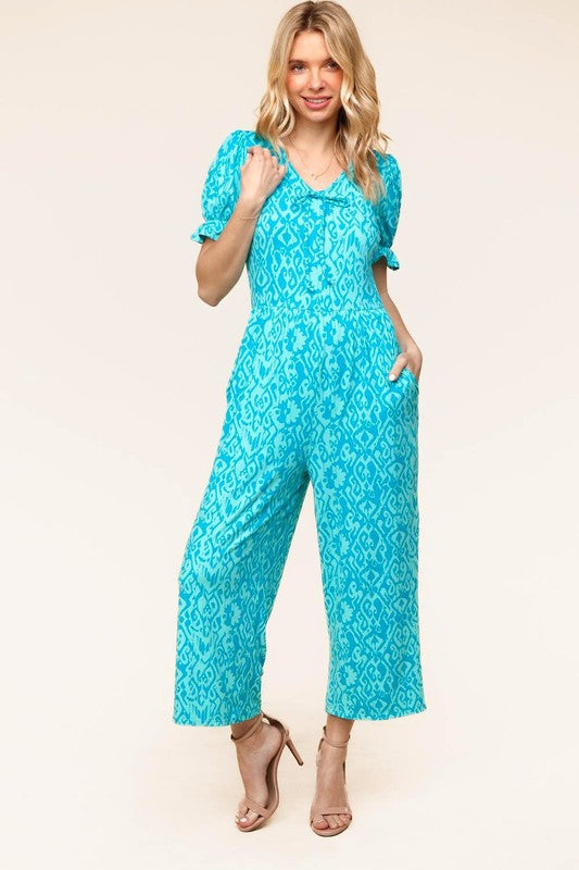 Woman wearing a blue floral jumpsuit on a beige background