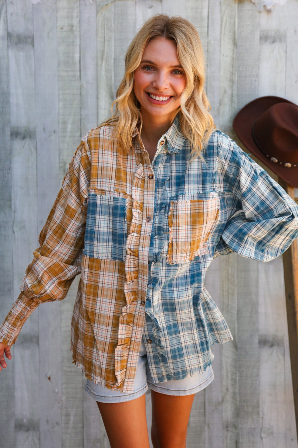 Woman wearing a plaid shirt and shorts standing against a wooden wall.