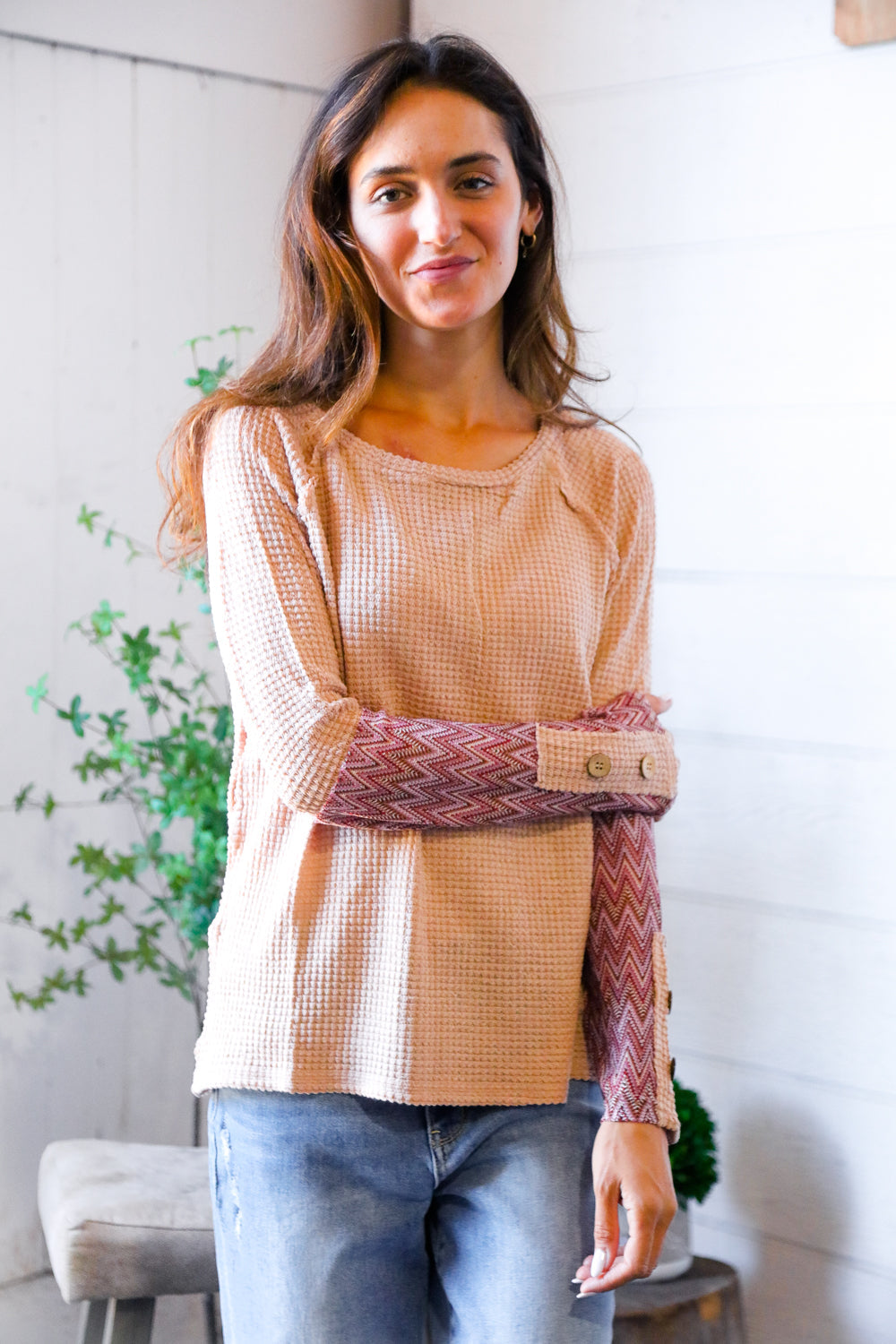 Woman wearing a beige and brown patterned top with a white background