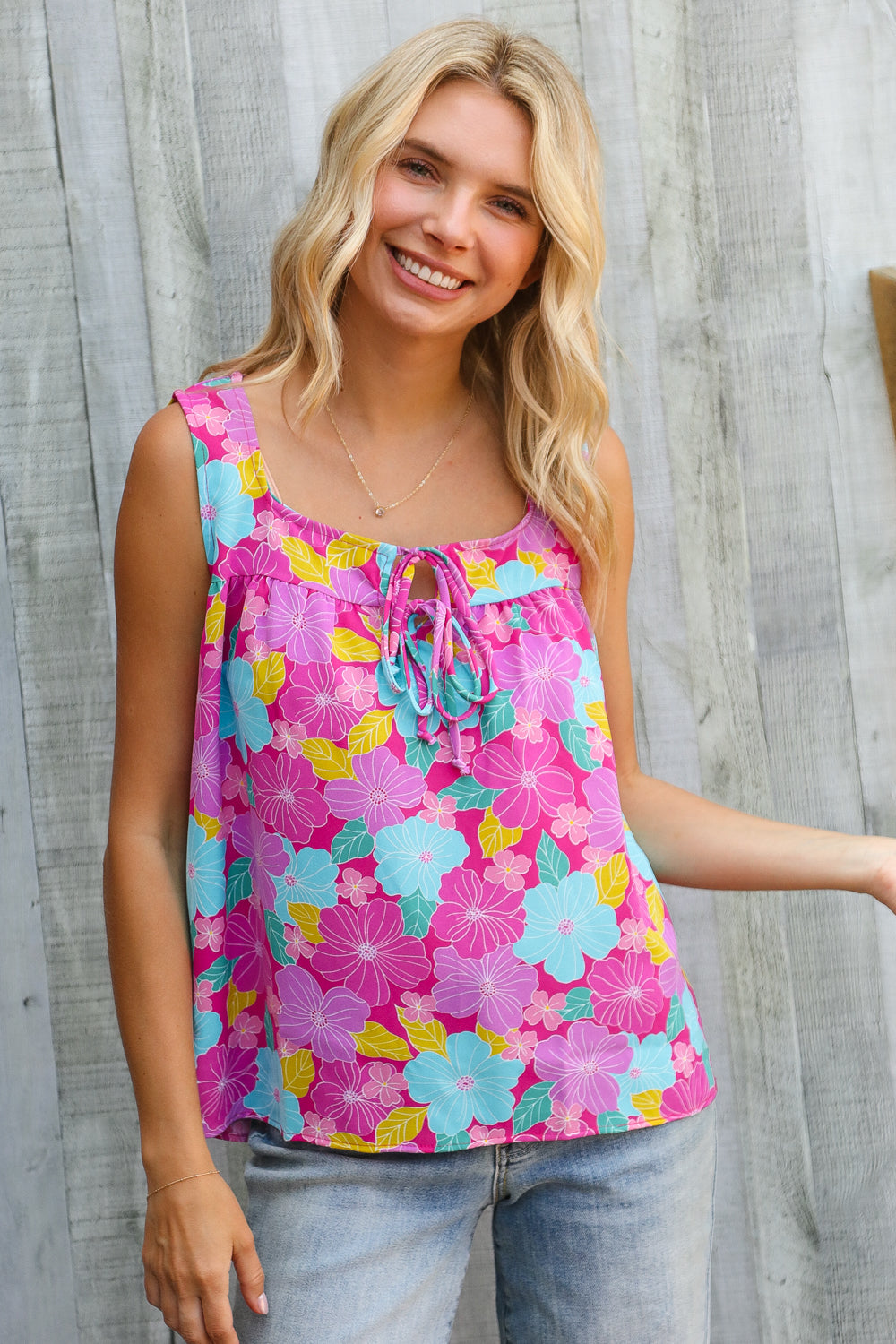 Woman wearing a colorful floral tank top against a wooden background