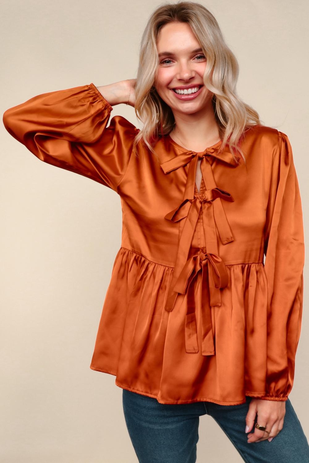 Woman wearing a rust-colored blouse with a beige background