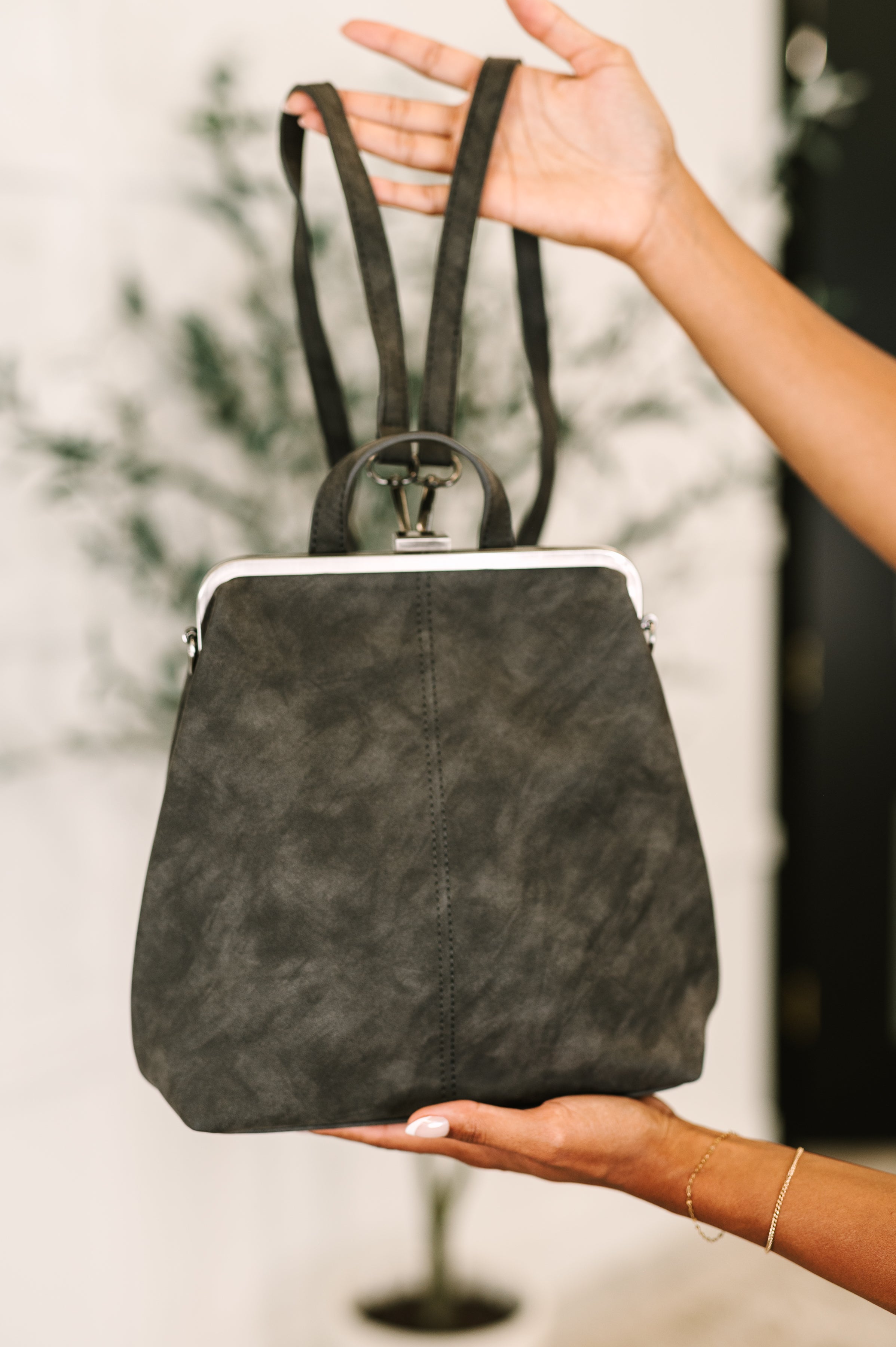 Gray backpack held by a person with a blurred background
