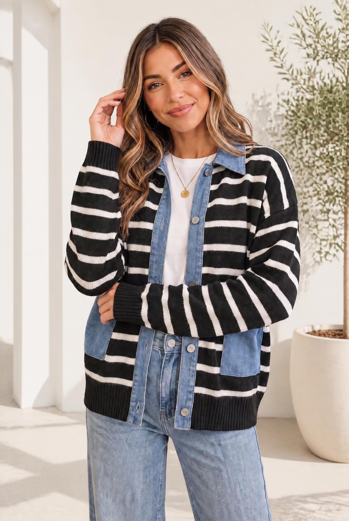 Woman wearing a black and cream striped knit jacket with denim panels, button front, and ribbed cuffs.