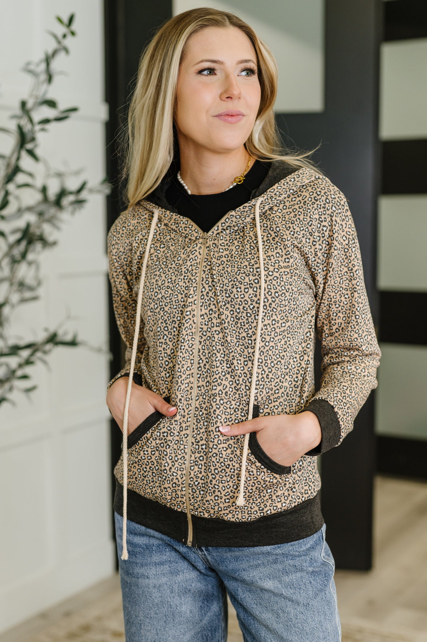 Woman wearing a patterned hoodie jacket and jeans indoors