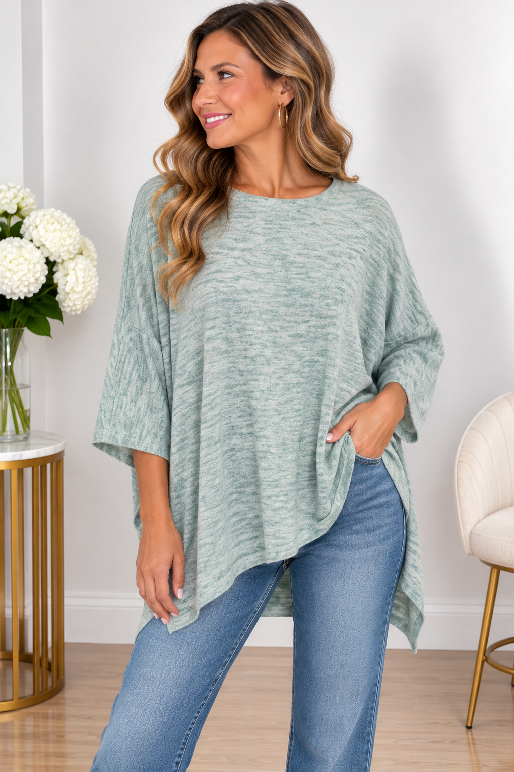 Woman wearing a jewel green top with a wide neckline, three-quarter sleeves, and asymmetrical hem.