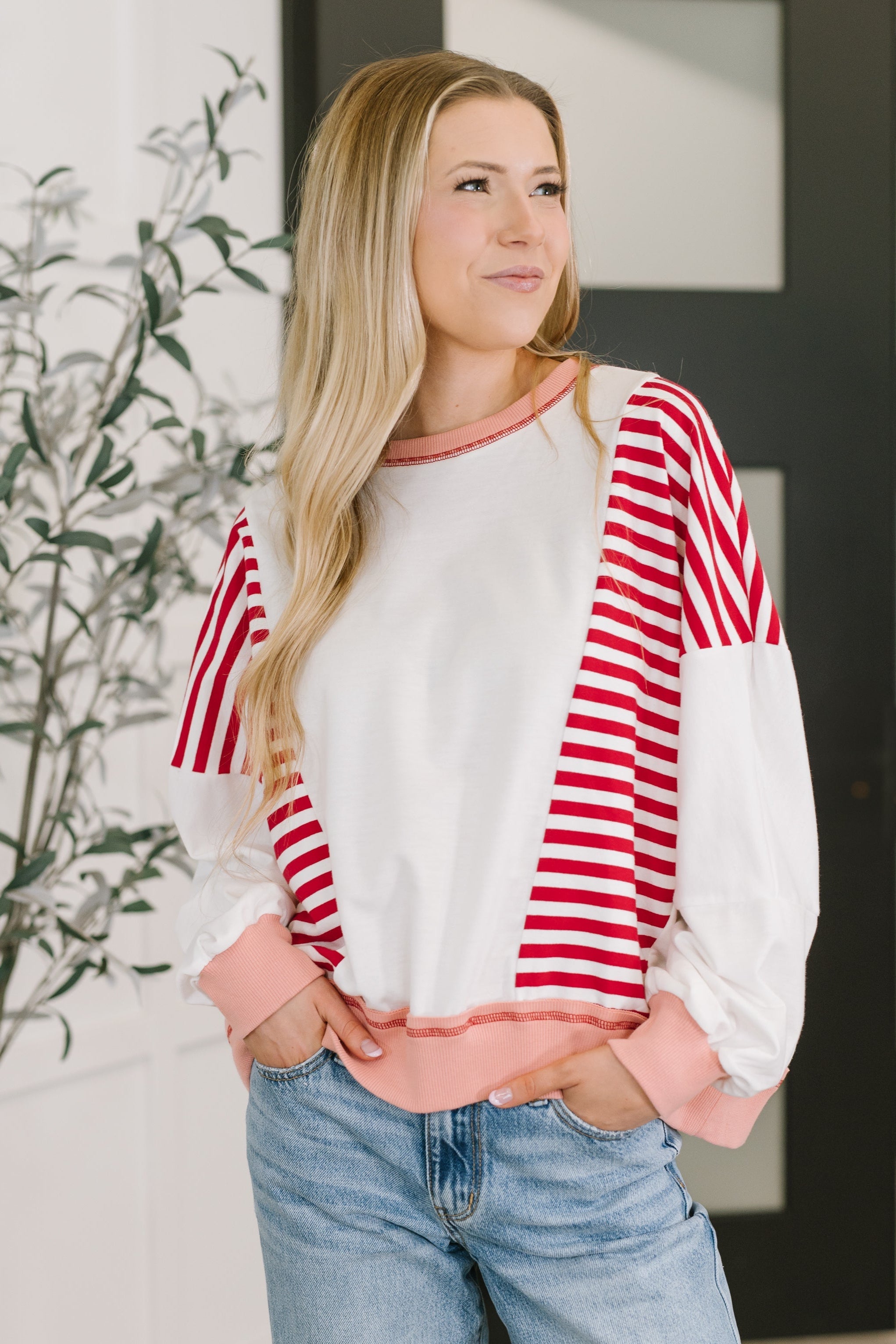 Woman wearing a red and white striped sweatshirt with dolman sleeves and ribbed cuffs.