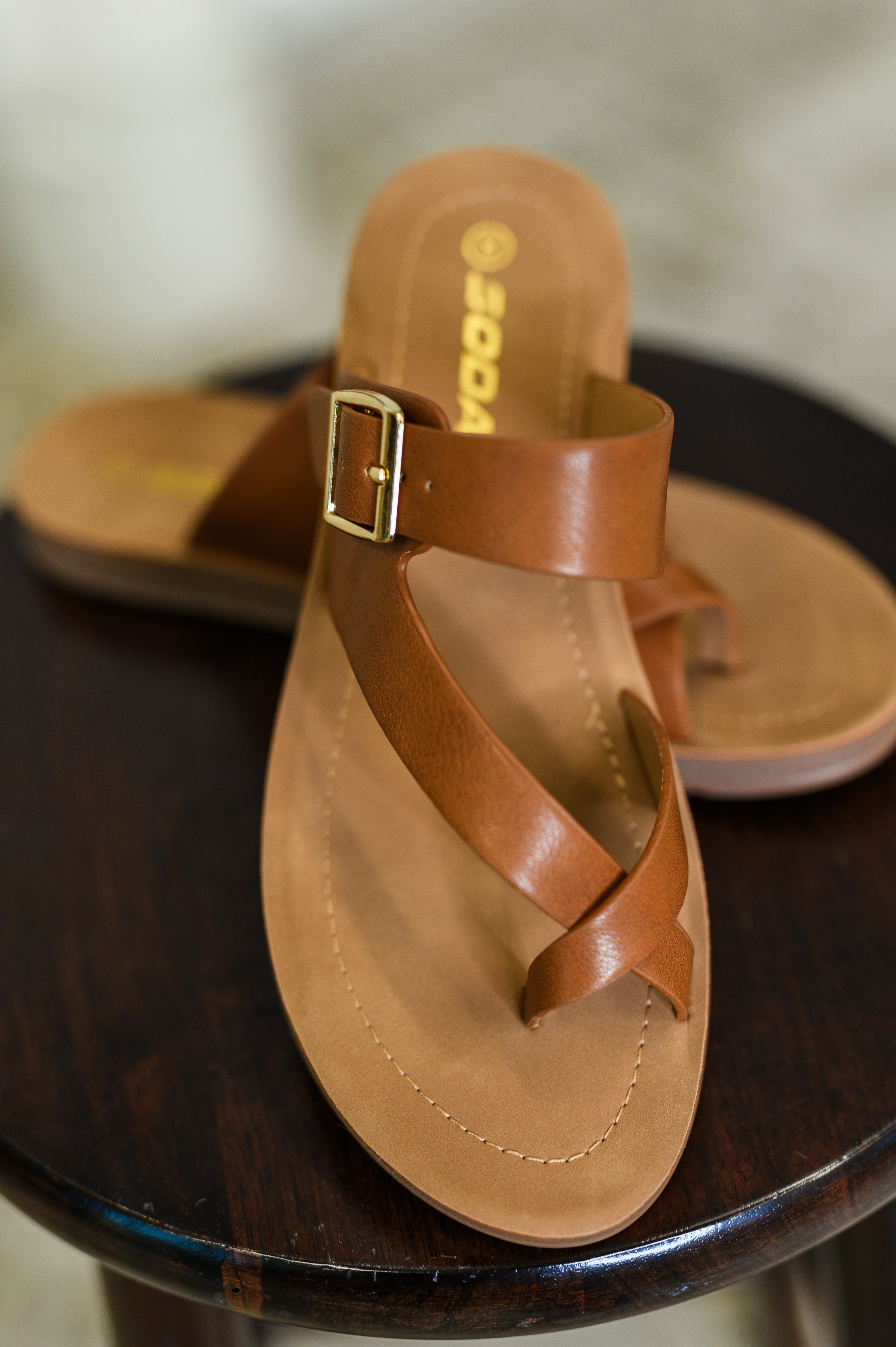 Women's brown sandal with a buckle on a dark surface