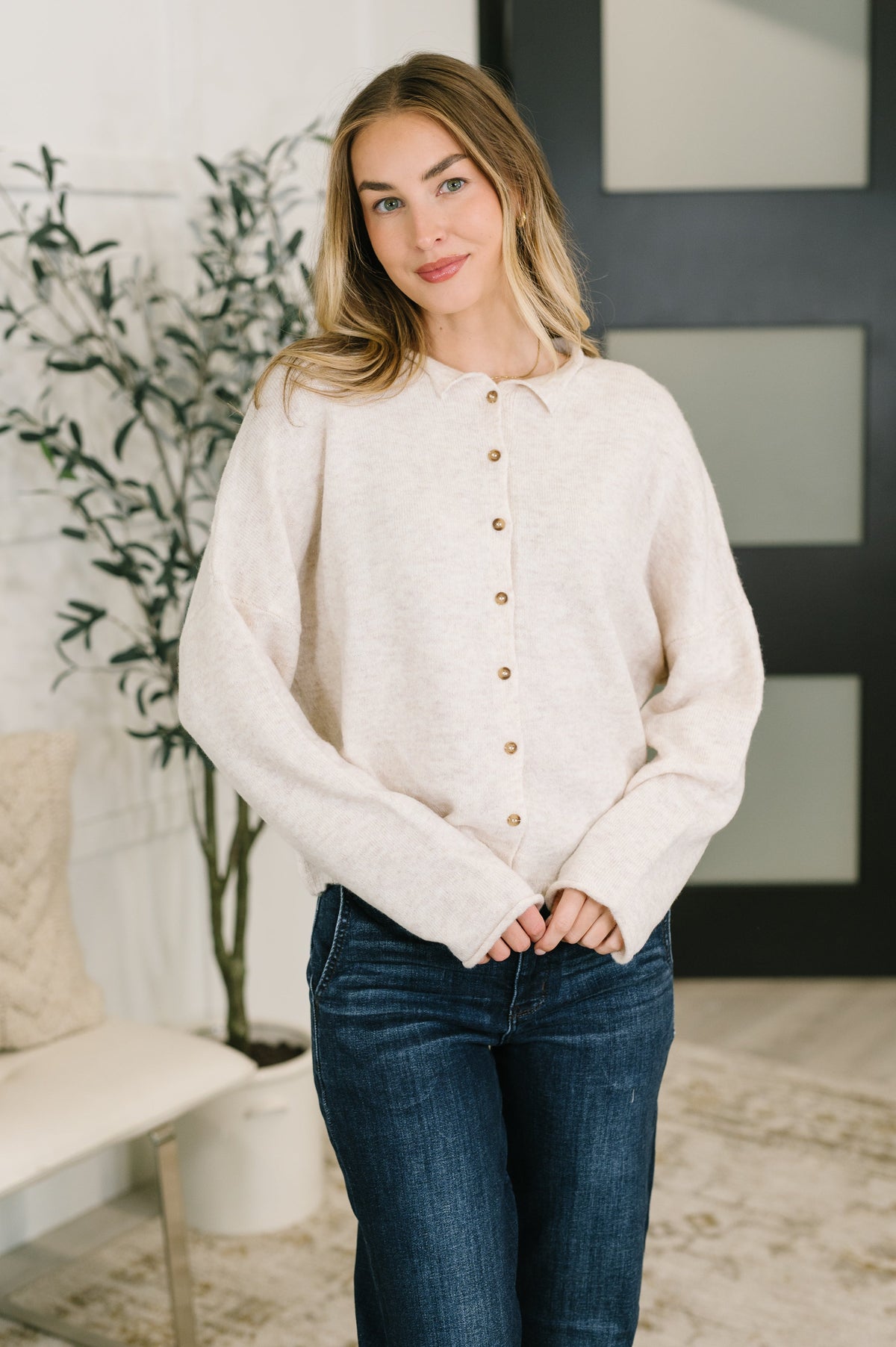 A woman wearing a heathered beige button down with a collared neck and rolled sleeve cuffs.