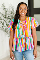 Woman wearing a colorful striped blouse with a blurred indoor background