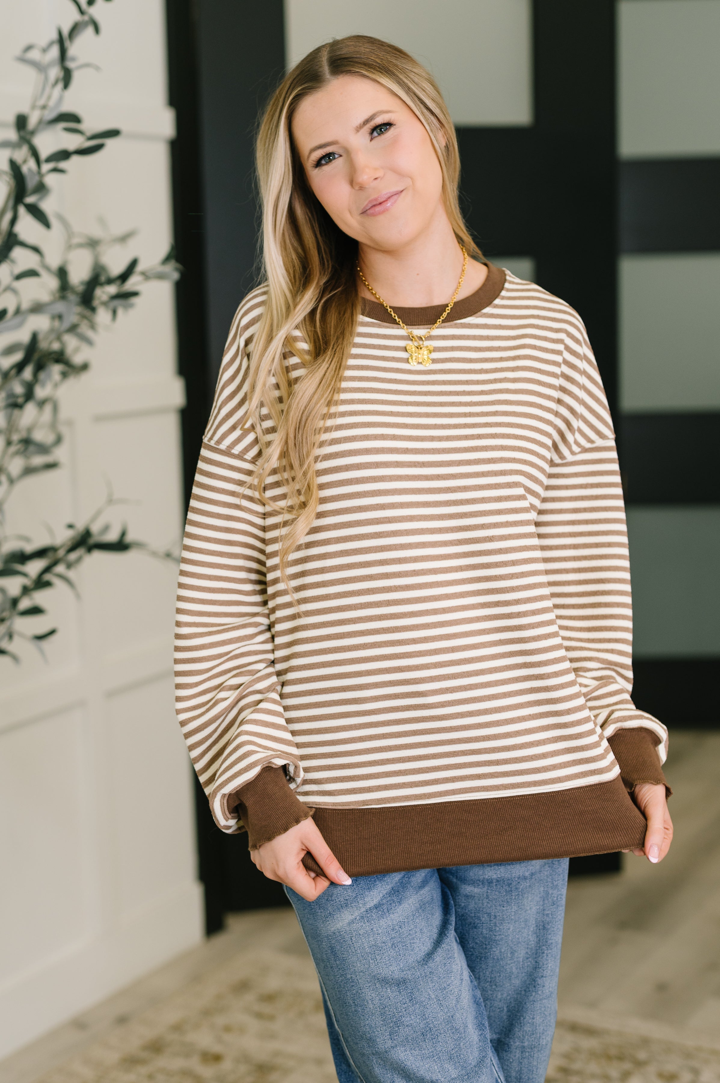 Woman wearing a striped long sleeve shirt with brown trim in a home setting