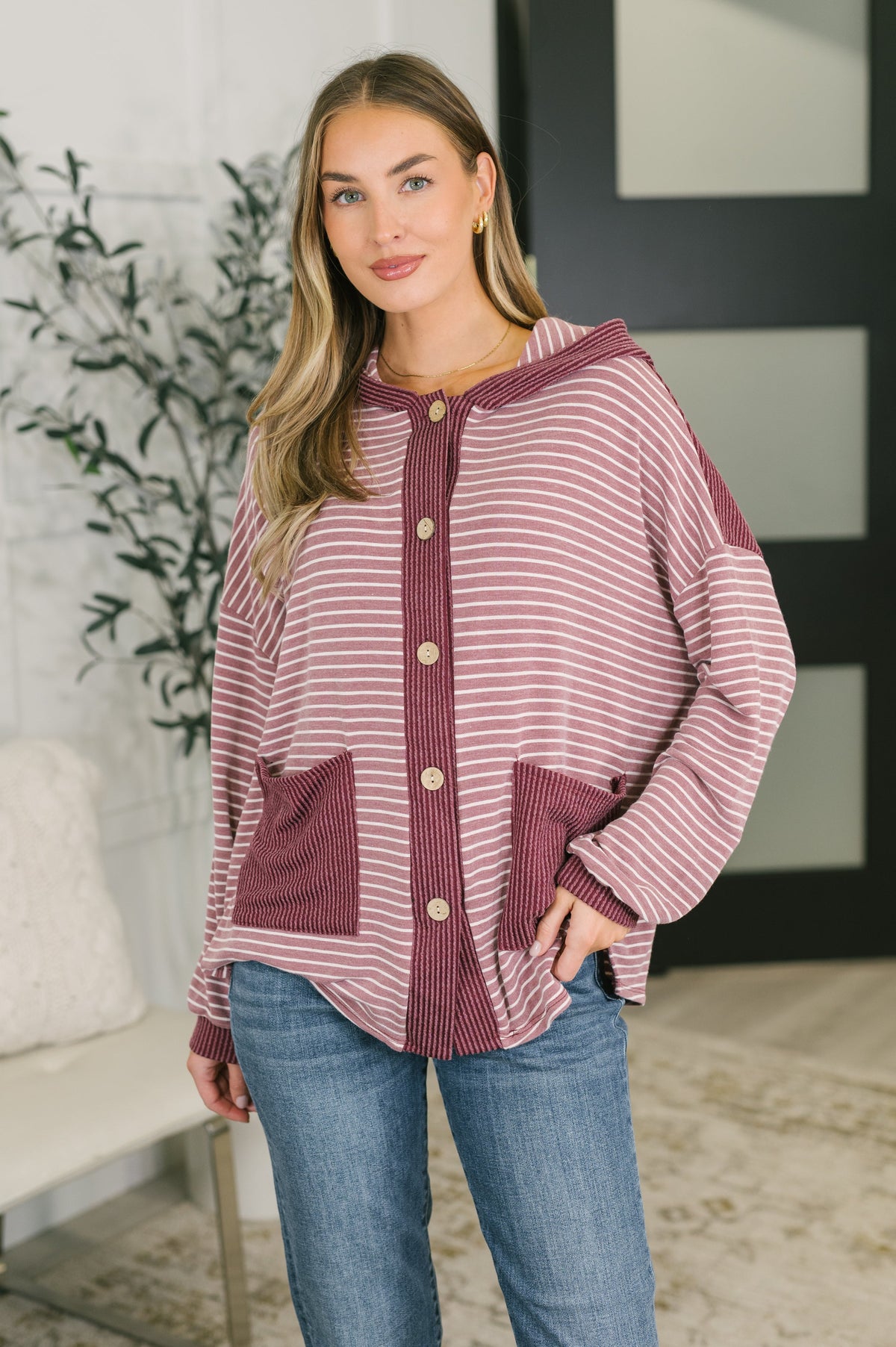 Model wearing a striped button-down hooded top with contrast detailing and patch pockets.