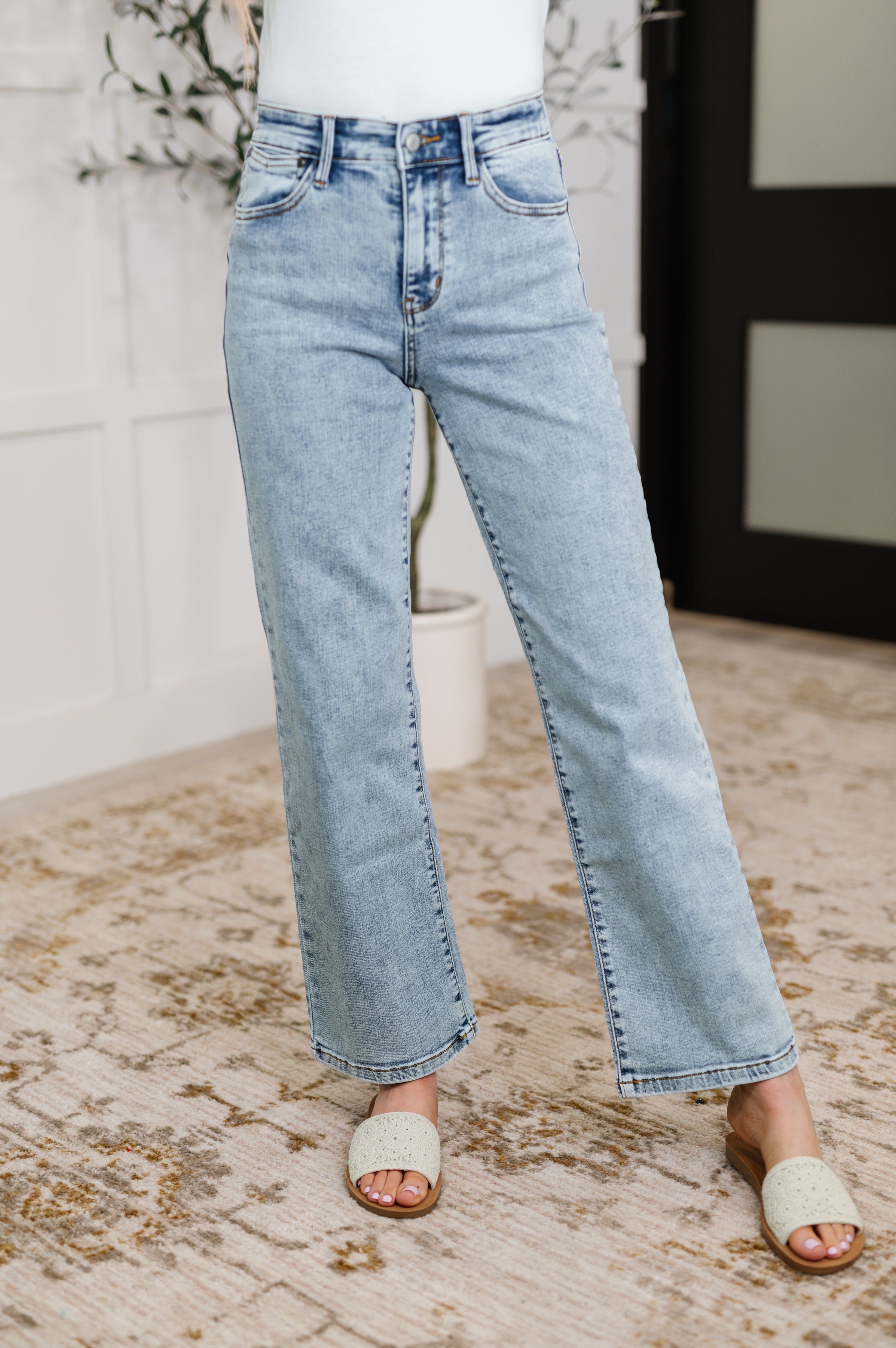 Light blue jeans worn by a Woman on a textured floor.