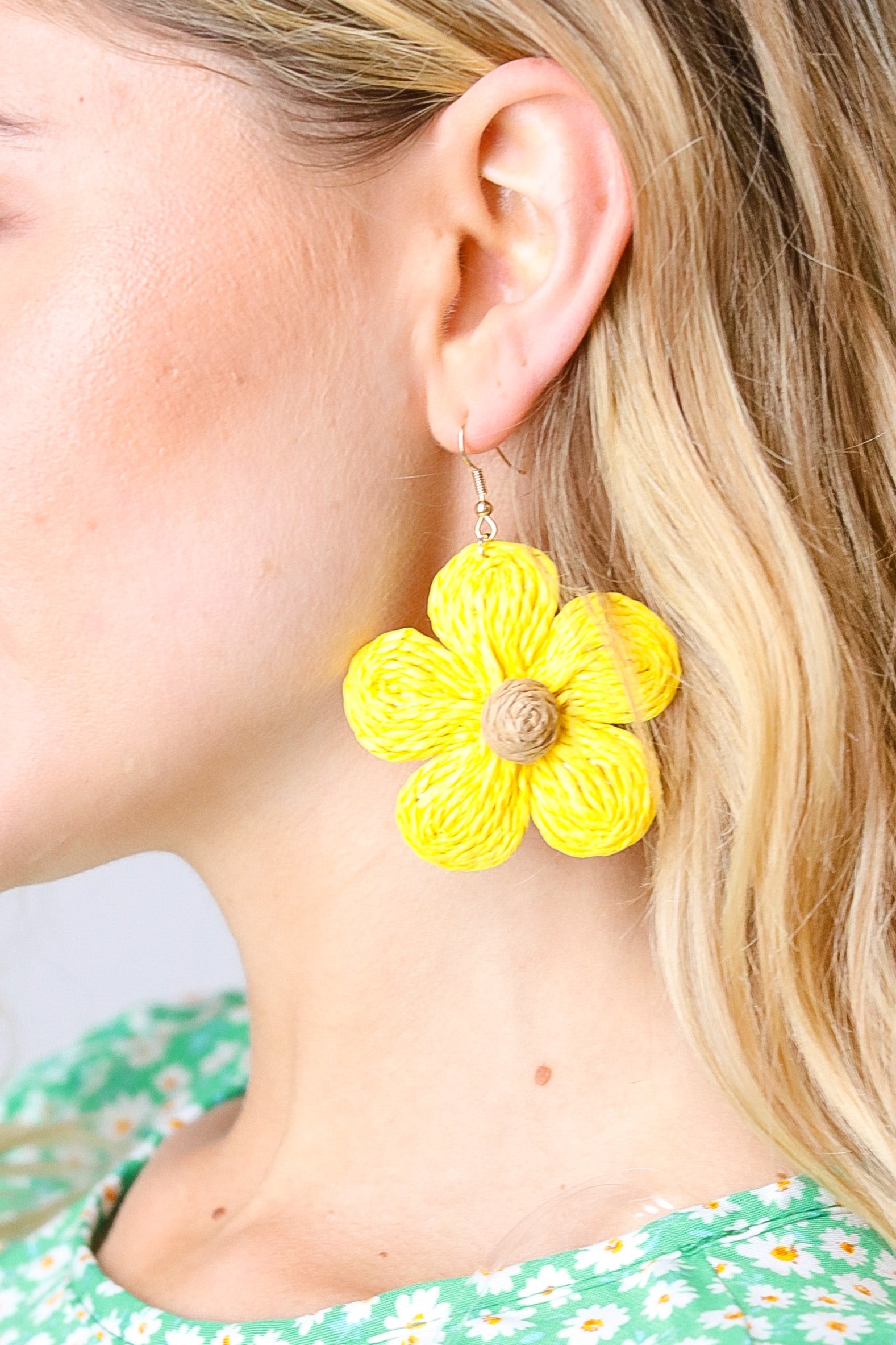 Yellow flower-shaped earring worn by a person with blonde hair.