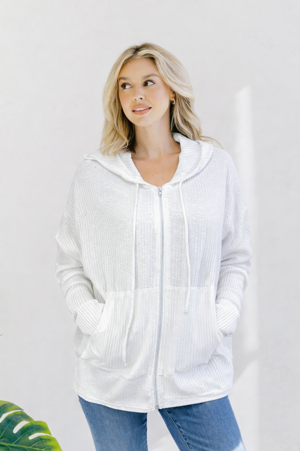 Off-white zip-up hoodie with an oversized fit, ribbed fabric, and adjustable hood.