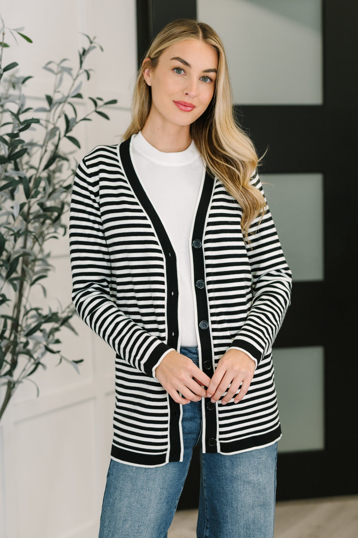 A woman wearing a black and white striped cardigan with button closures and a V-neckline.