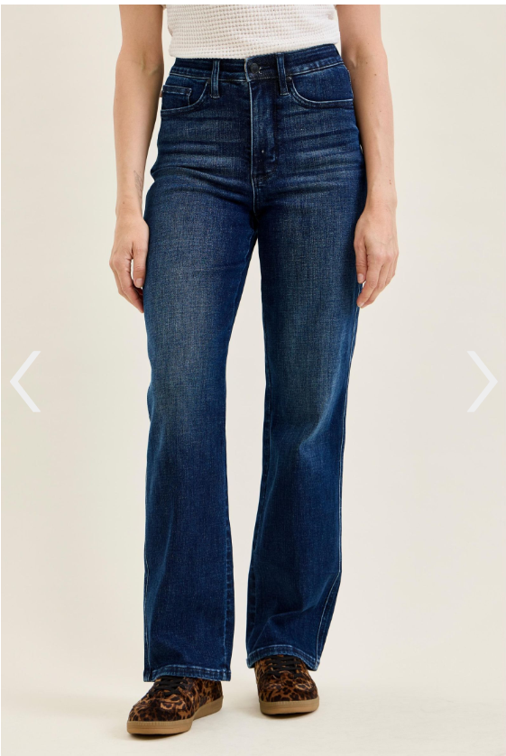 A person wearing high-waisted, straight-leg jeans in dark midnight blue with a zip fly.