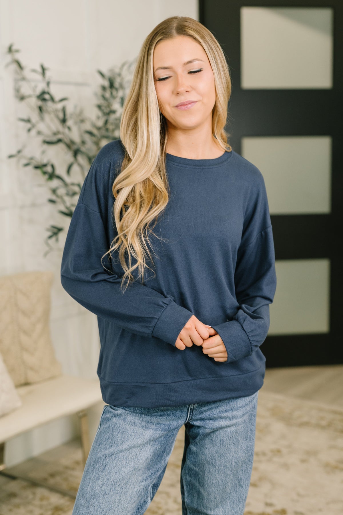 Model wearing a navy long sleeve top with drop shoulders and banded cuffs.