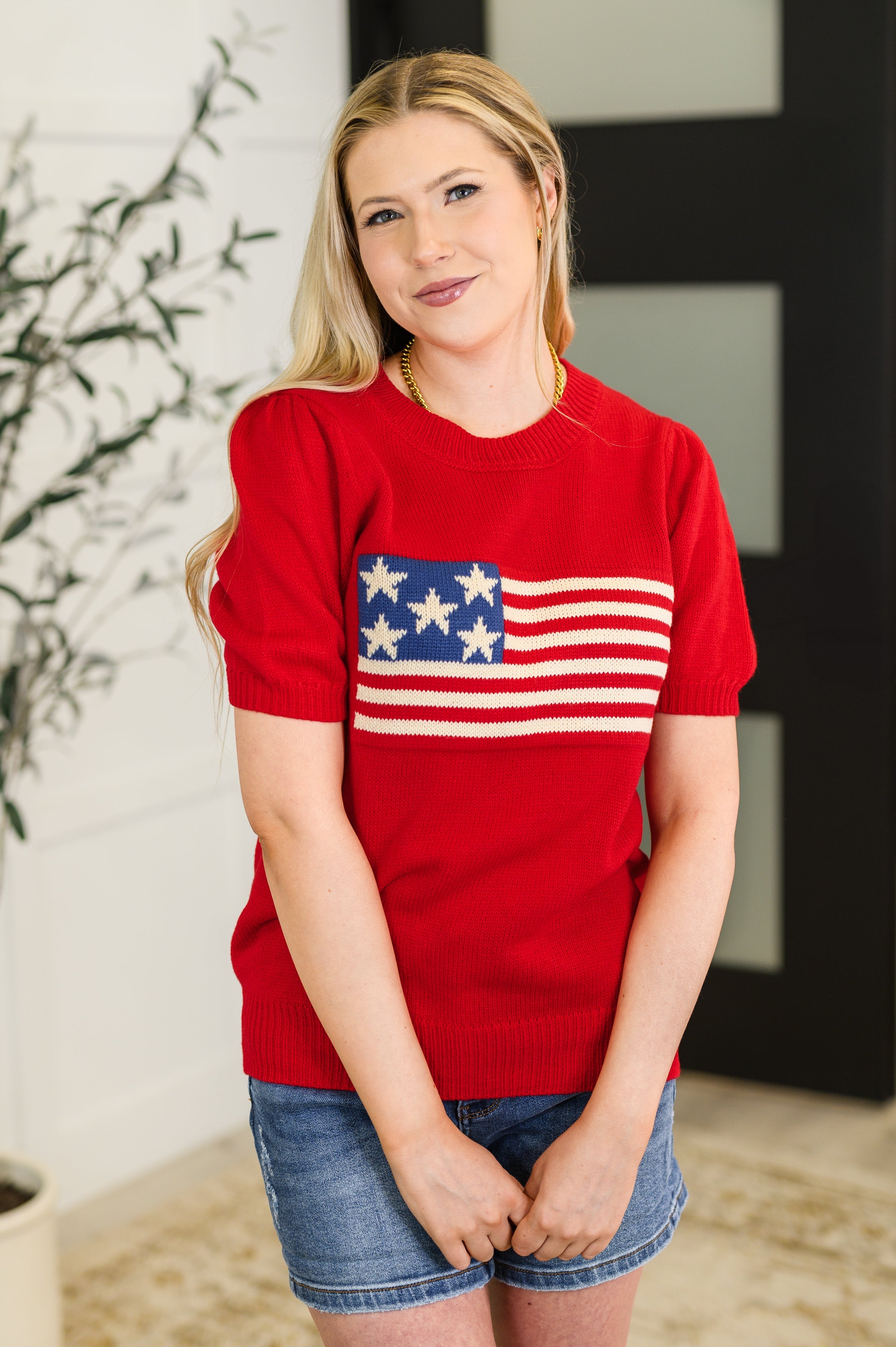 Woman wearing a red sweater with an American flag design indoors.