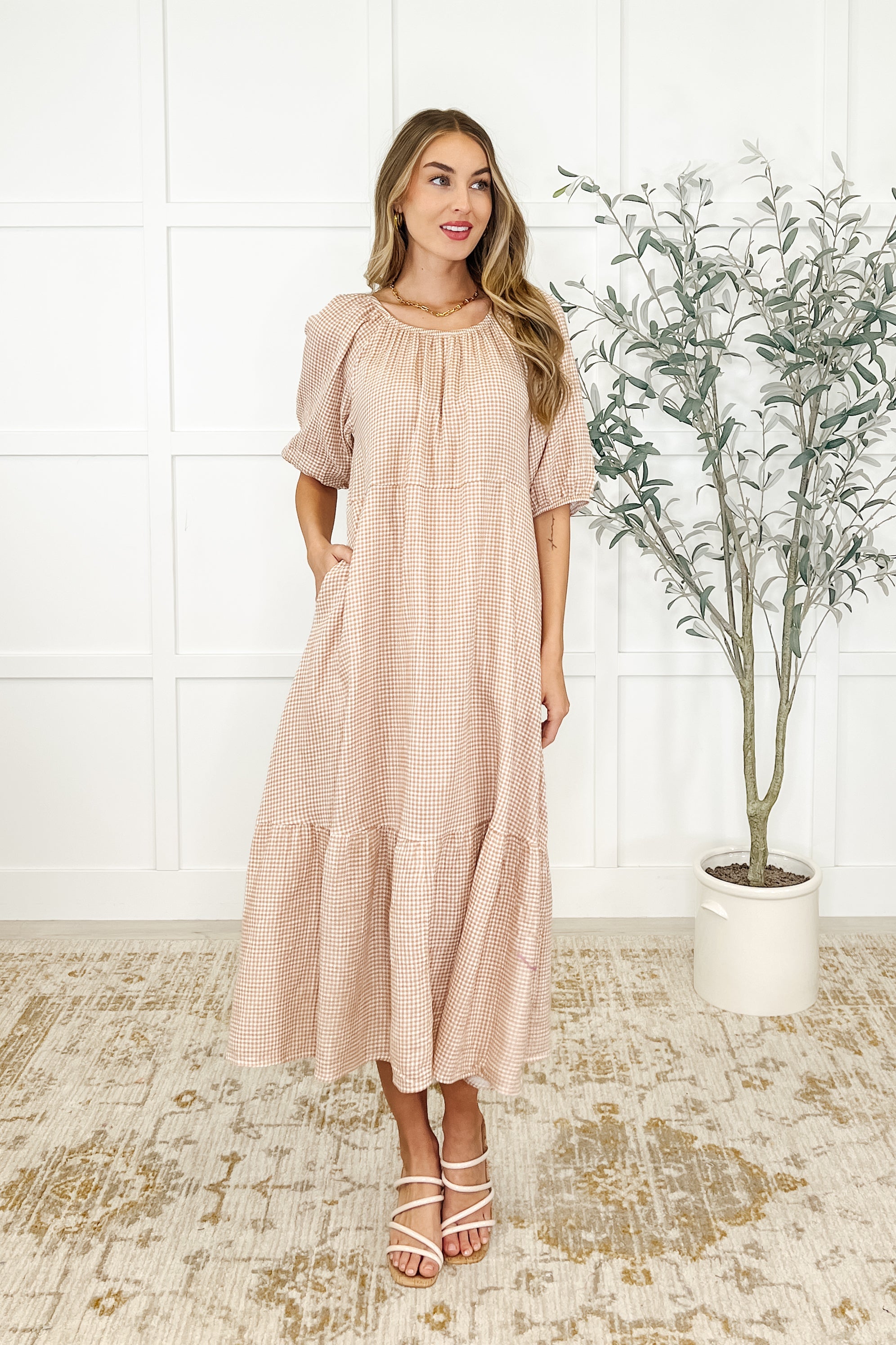 Woman wearing a beige dress with short raglan sleeves and a round neckline, paired with strappy sandals.