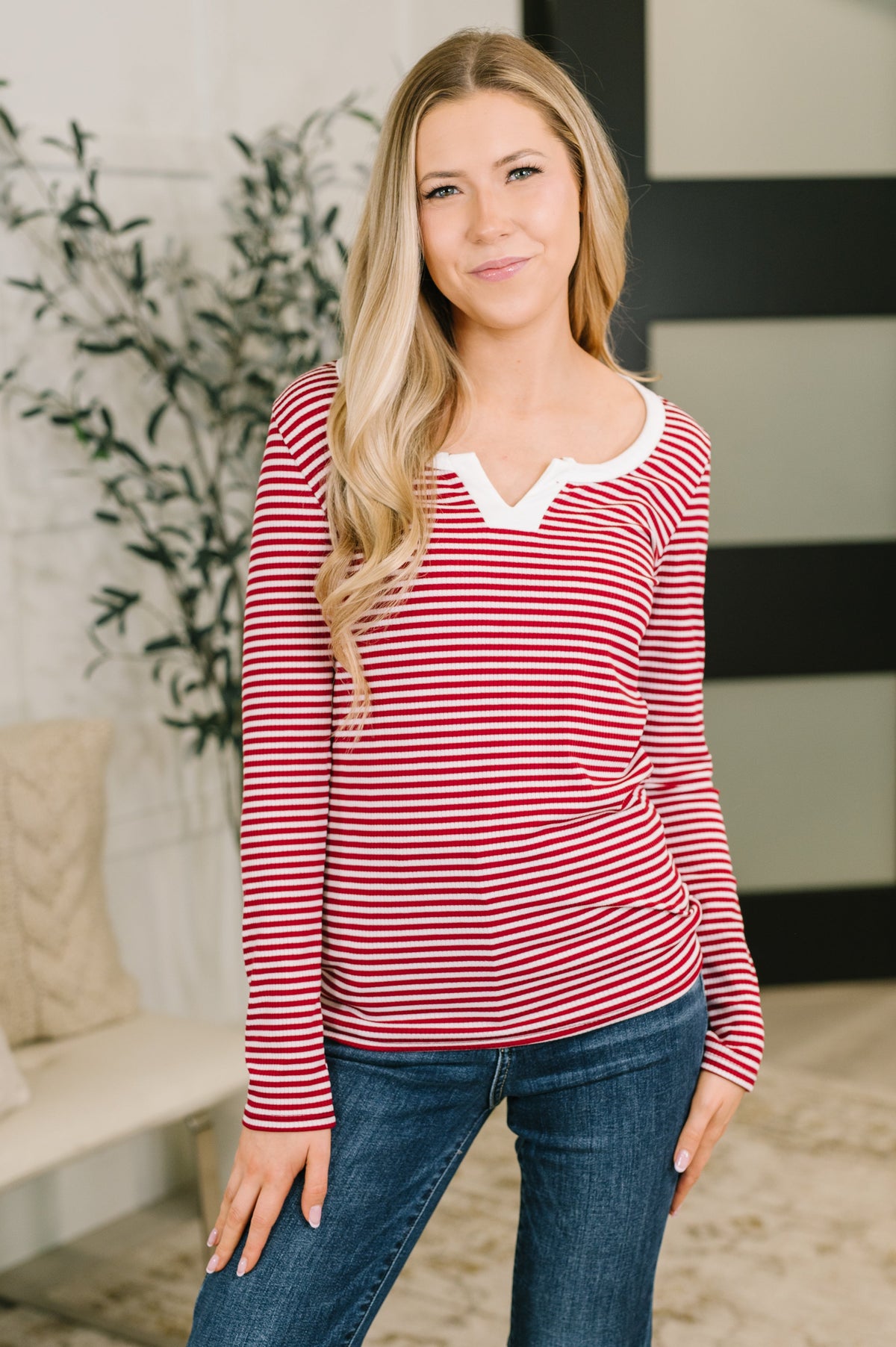 A woman wearing a burgundy ribbed knit top with a scooped split neckline and long sleeves.