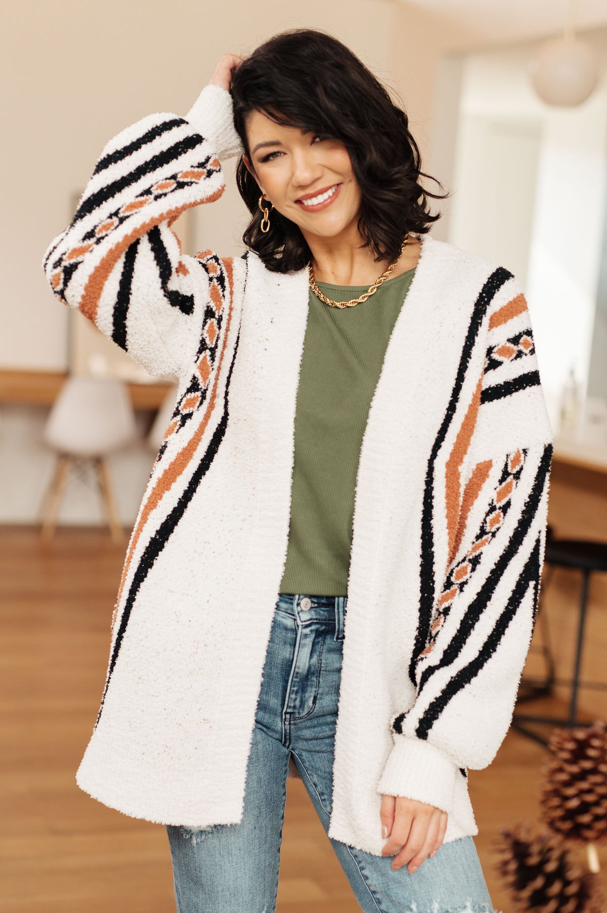 A woman wearing a multi-color Aztec print cardigan with an open front and dropped shoulders.