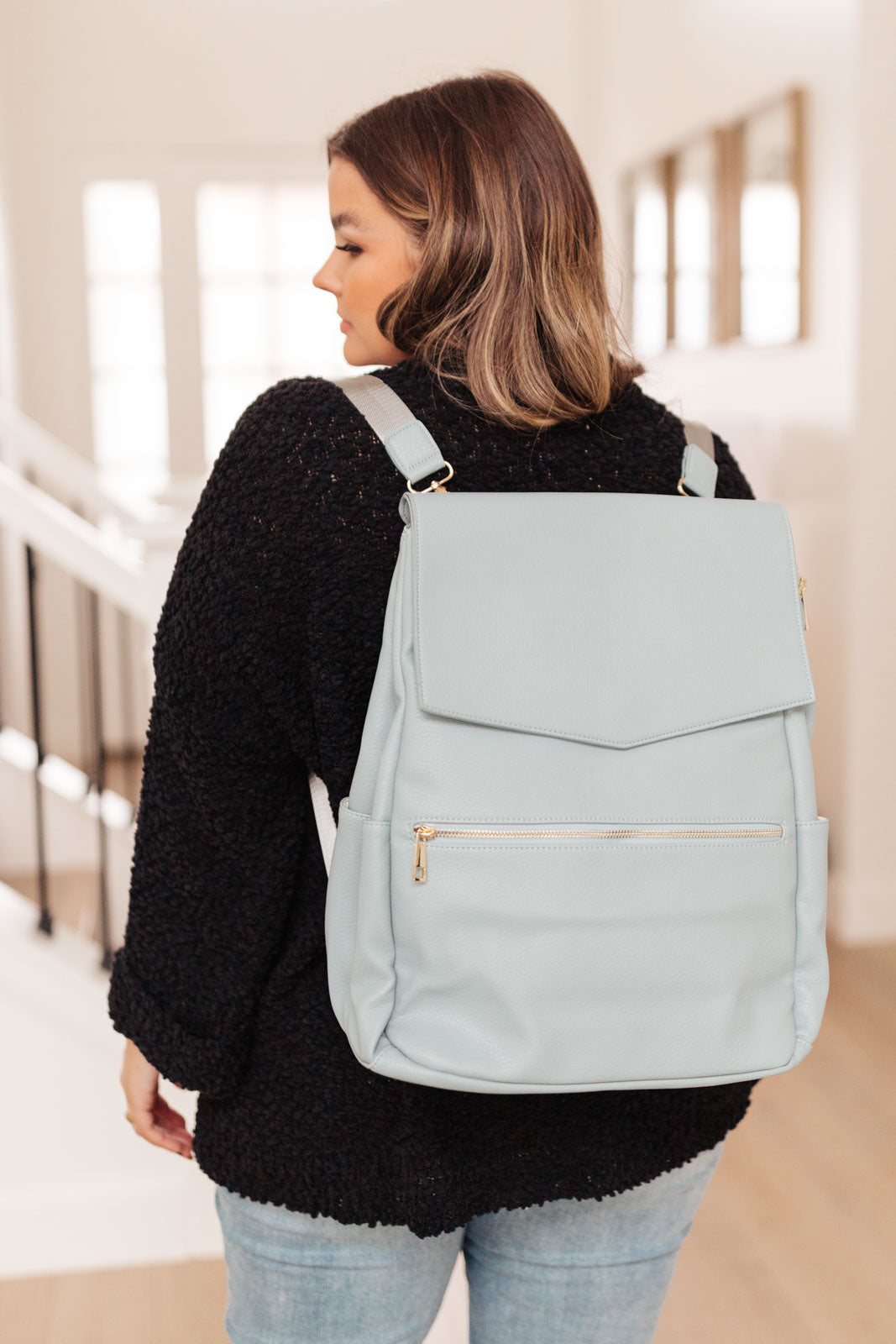 Blue baby bag with multiple pockets and adjustable straps worn as a backpack by a model.