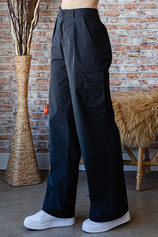 Woman wearing black wide-leg pants with a brick wall and decorative items in the background