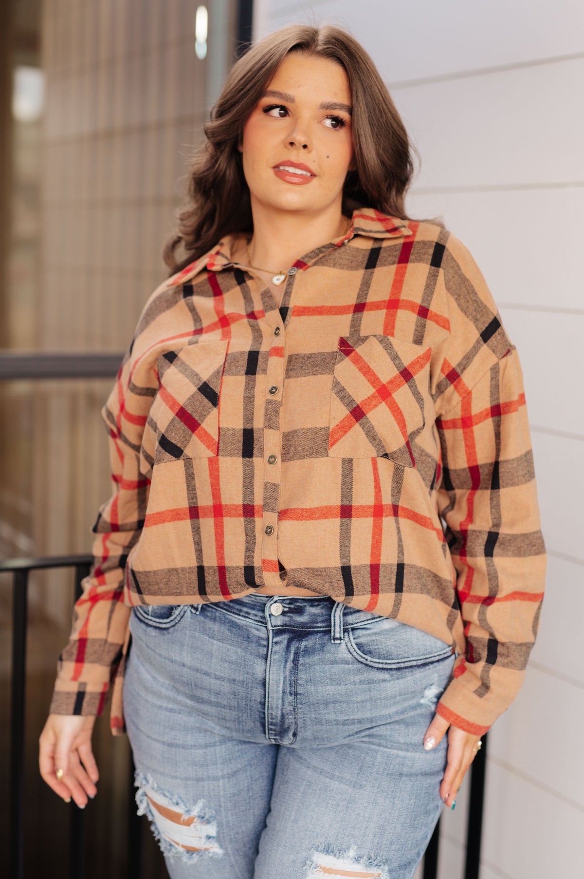 A model wearing a multicolor plaid button-up shirt with a collared neckline and dropped shoulders.
