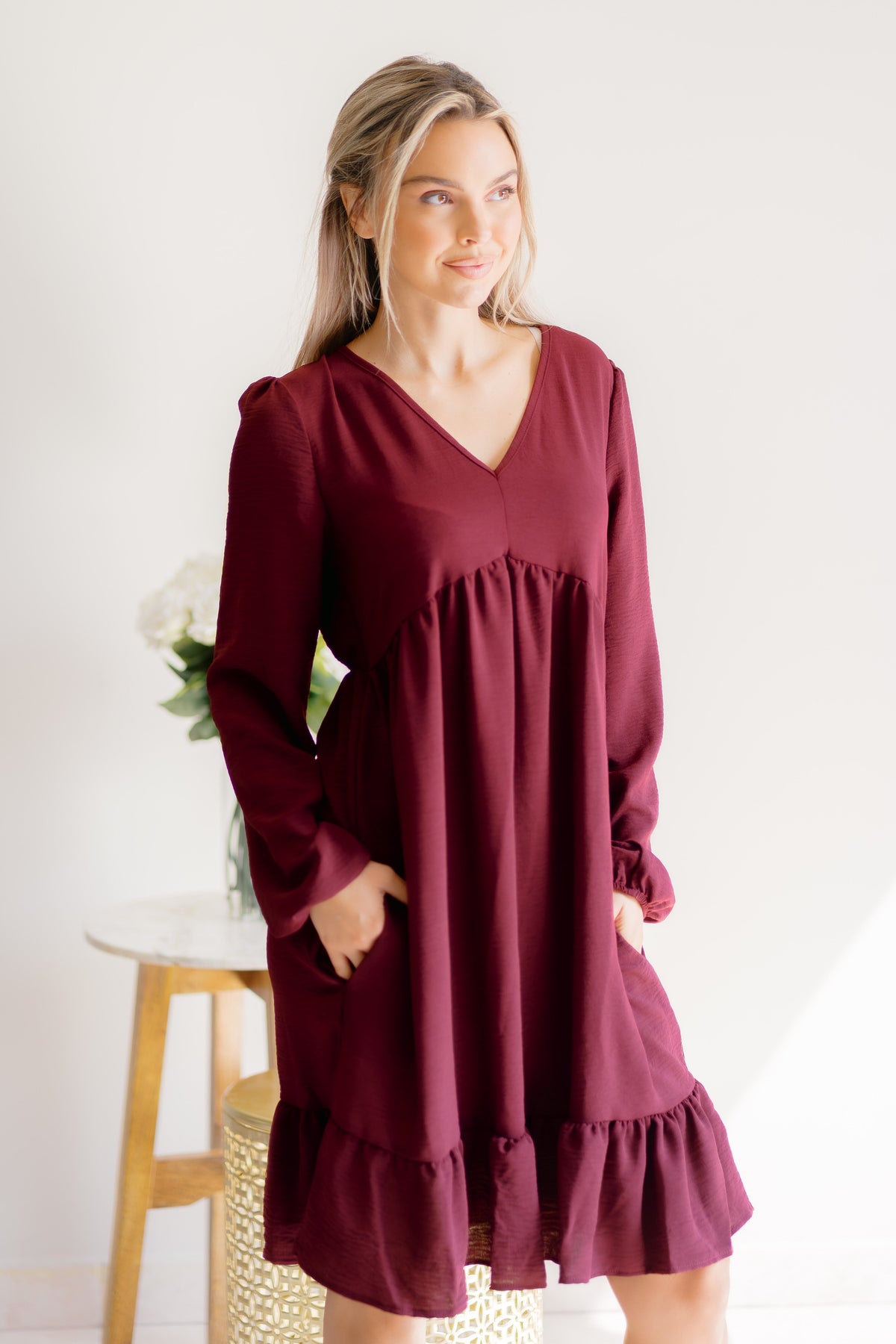 A woman wearing a burgundy dress with a flattering silhouette and V-neckline.