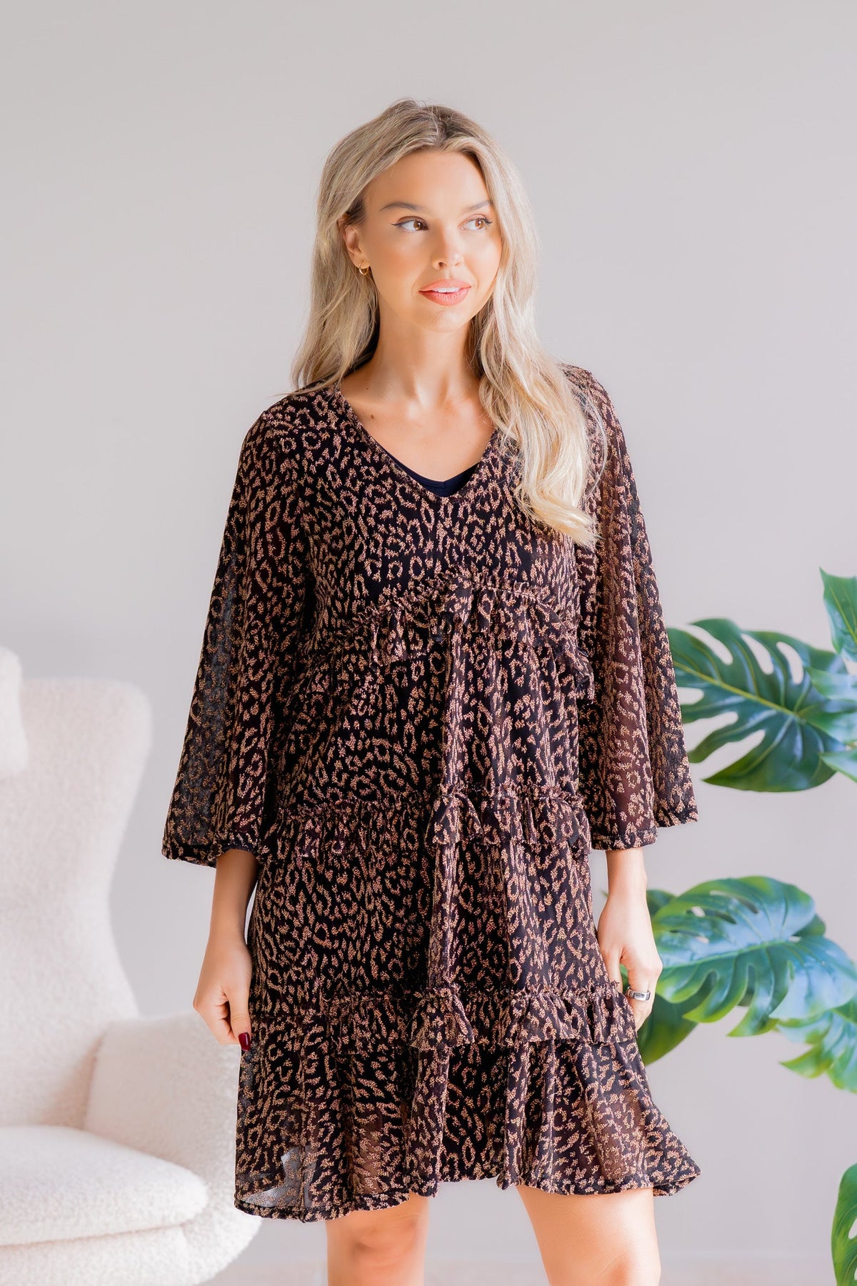 A woman wearing a black and gold animal print dress with a V-neck and 3/4 sleeves.