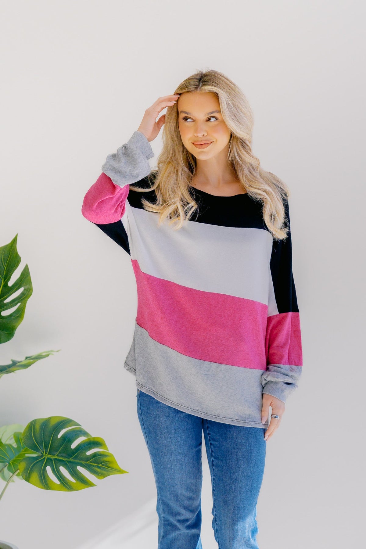 Woman wearing a colorblock pullover in black, pink, grey, and white with long bubble sleeves.