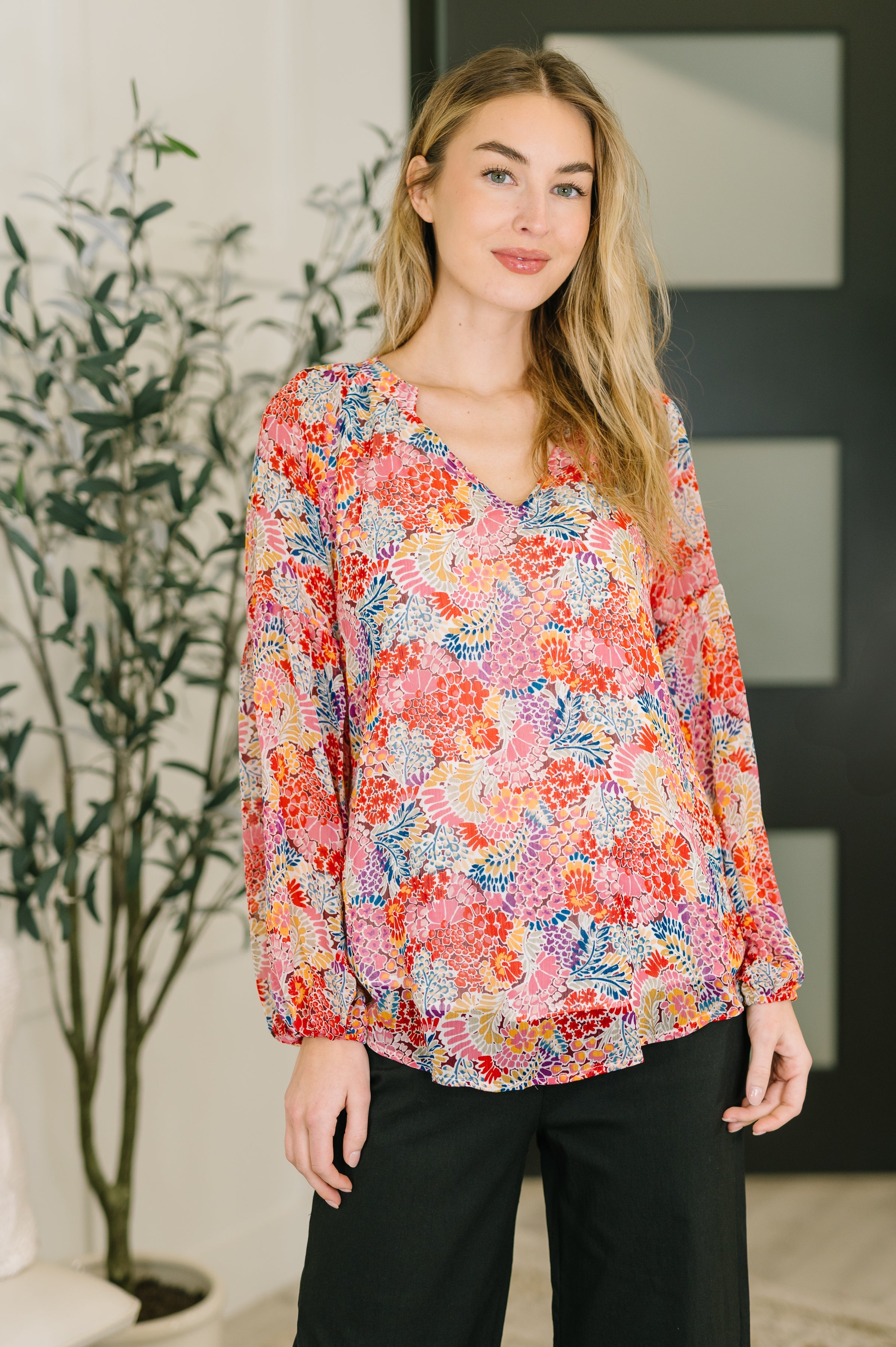 Model wearing a multicolor V-neck blouse with balloon sleeves and elastic cuffs.