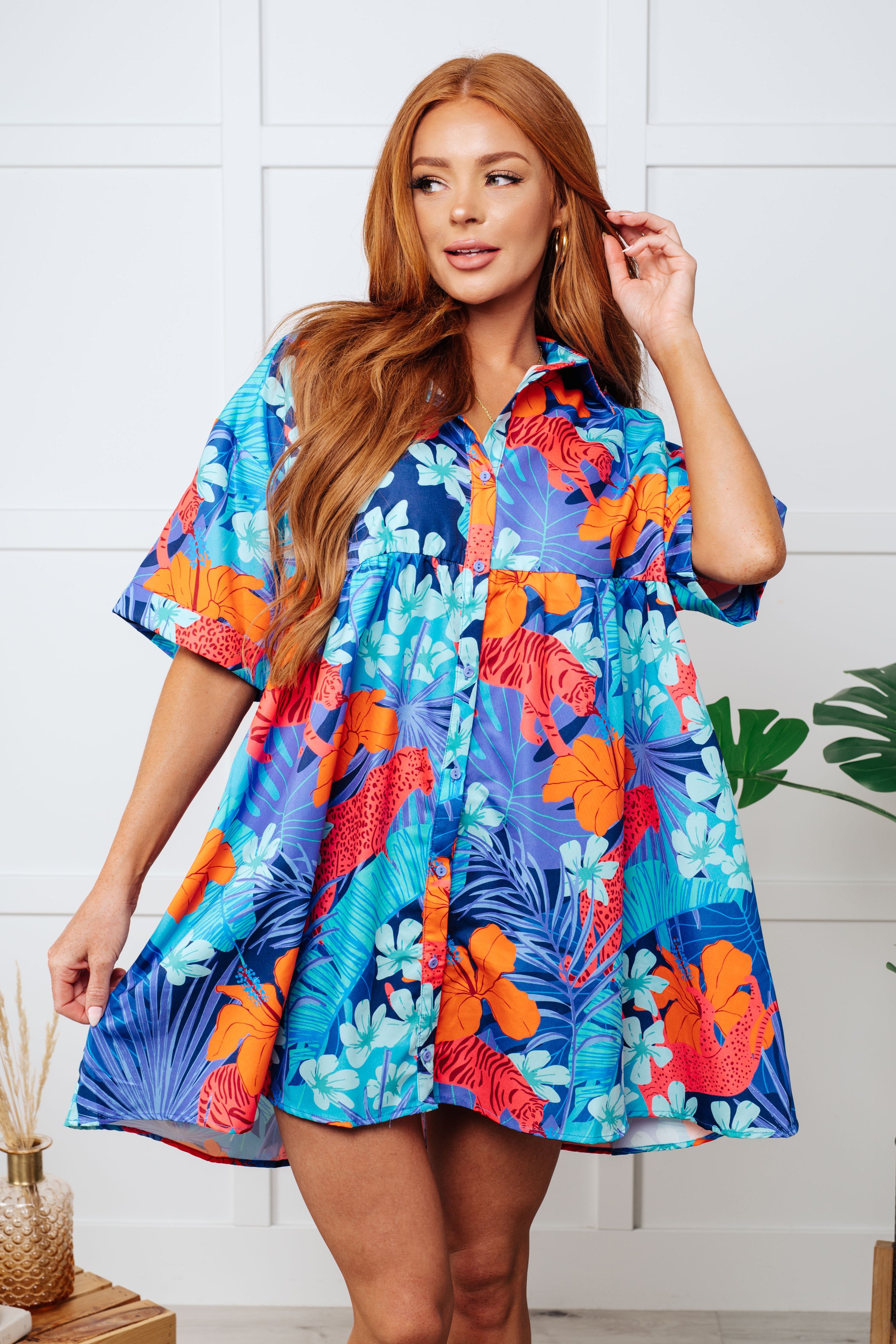 A woman wearing a blue collared dress with a floral pattern, featuring tacked sleeve cuffs and a tiered back.