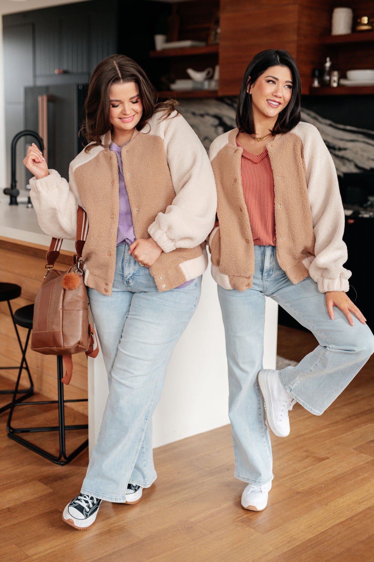 Two women wearing a Sherpa fleece bomber jacket with ribbed necklines and snap front closures.