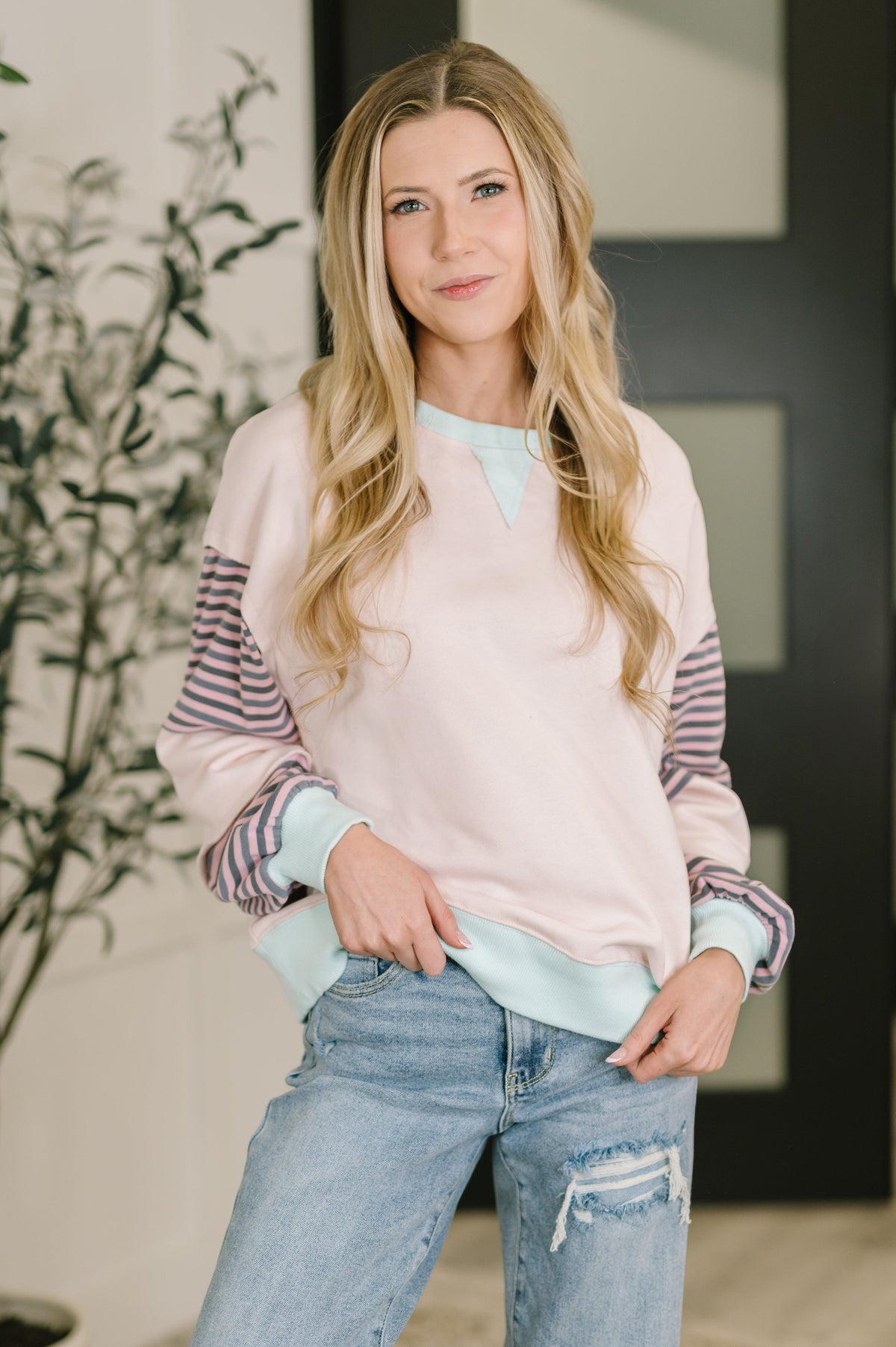 Woman wearing an oversized, color block pullover with ribbed neckline and cuffs, paired with jeans.