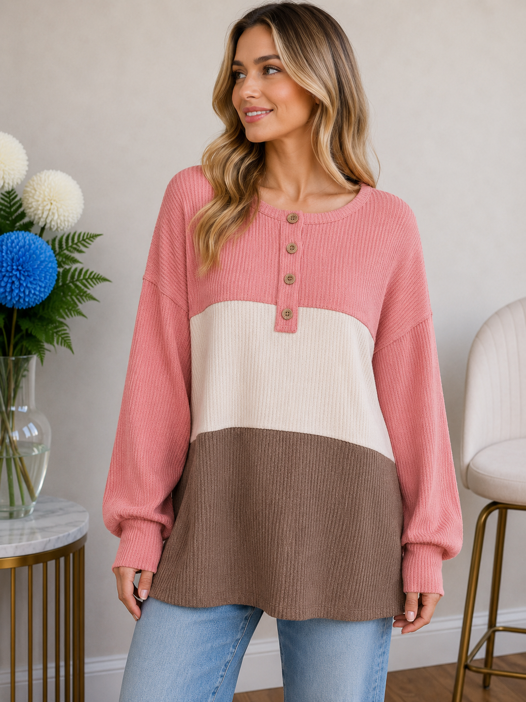 A woman wears a color block top in pink, beige, and chocolate with a round neckline and button details.