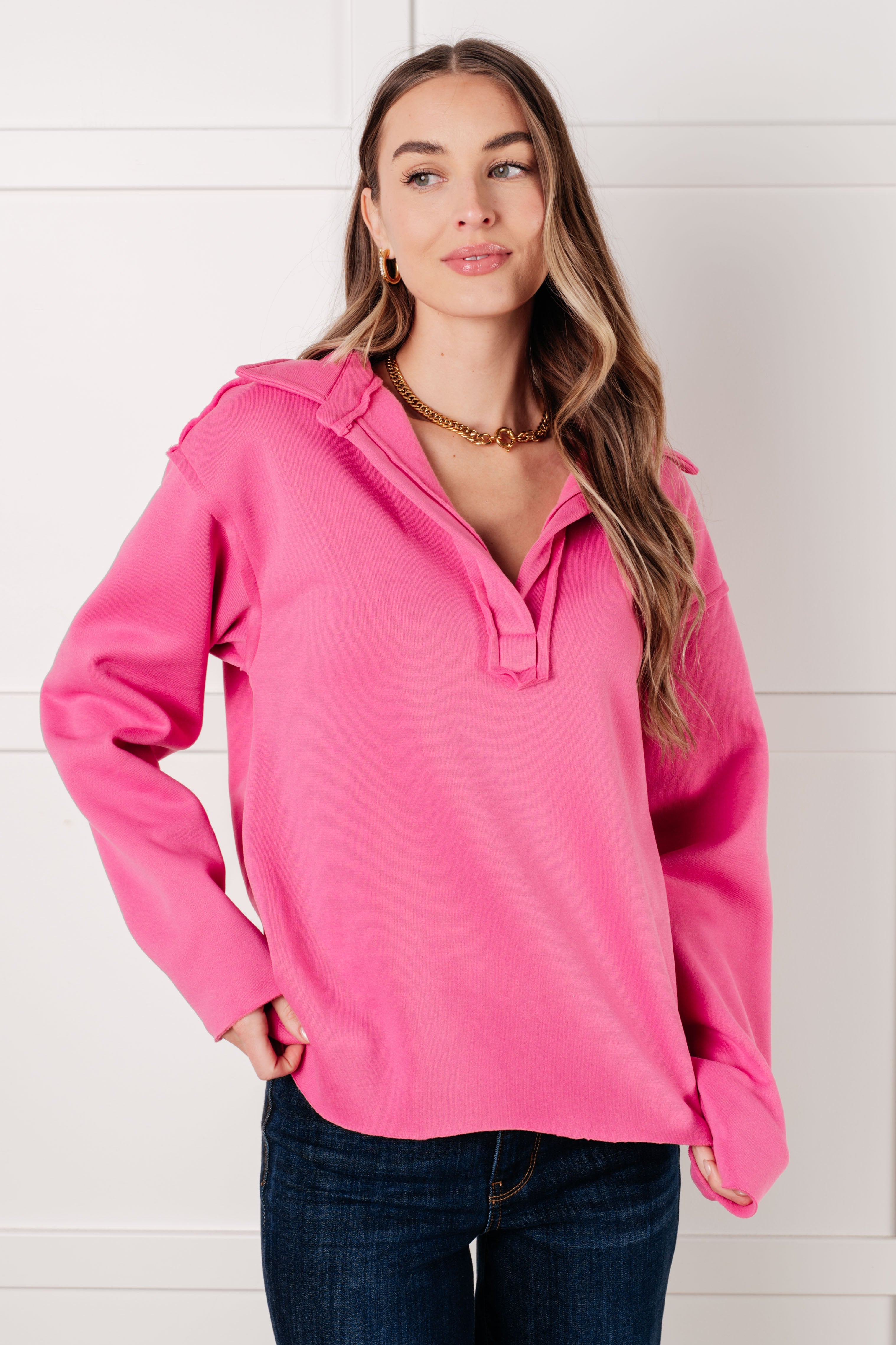 Hot pink collared pullover with a v-neck, drop shoulders, and raw hem, worn by a model.