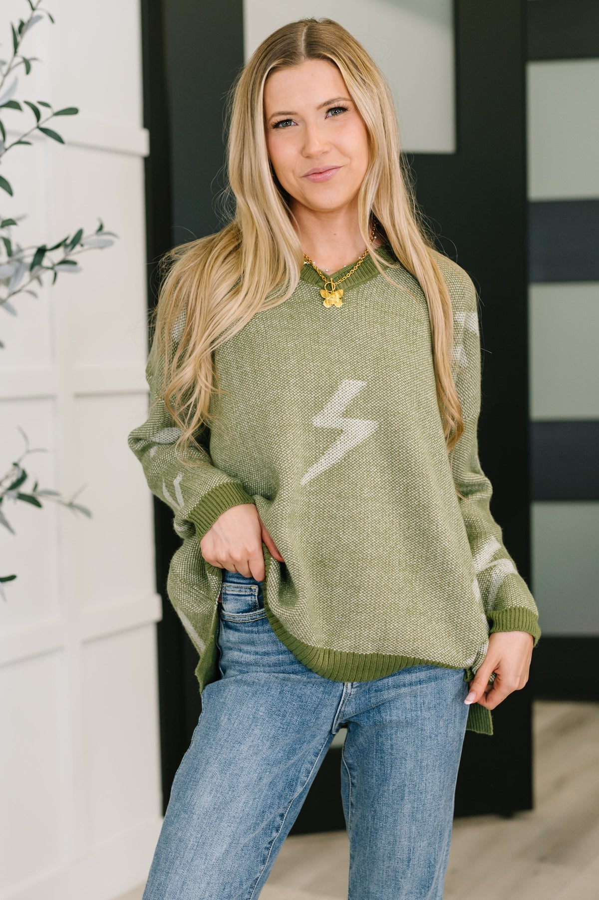 Woman wearing an olive mid-weight knit sweater with ribbed V-neck and drop shoulders.