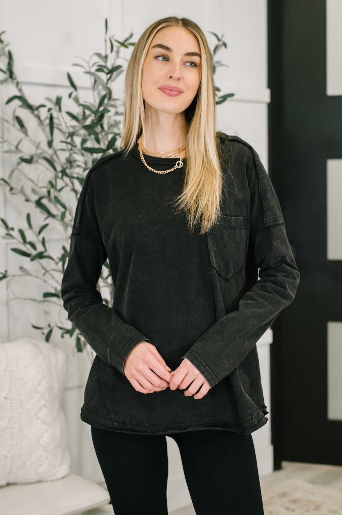 Black long sleeve top with drop shoulders, exposed seams, and a patch pocket.