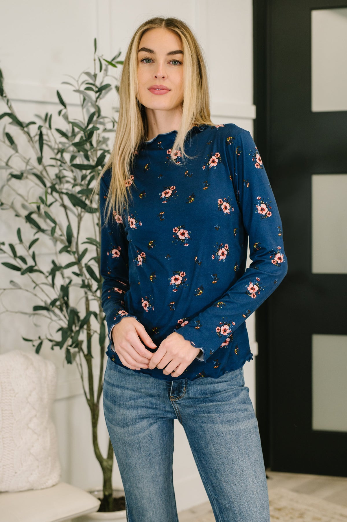 Navy long sleeve top with floral print and lettuce hem details worn by a model.