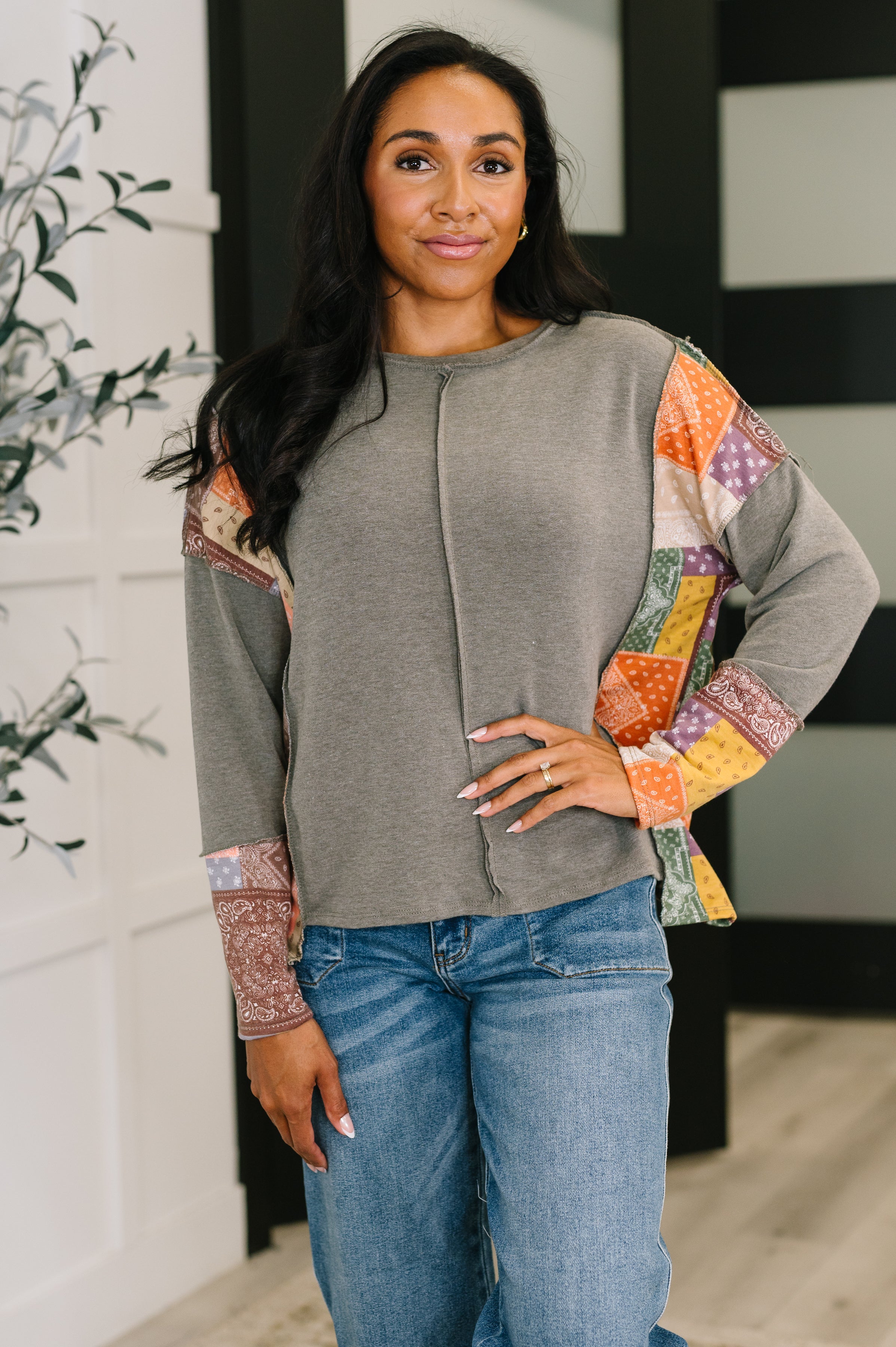 Color block long sleeve top in gray with multi-colored patterned accents on the sleeves, featuring a relaxed fit and exposed seams.