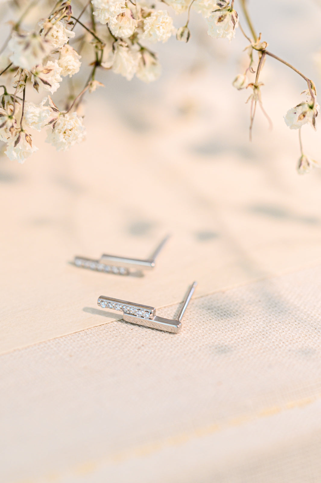 Sterling silver earrings with a stepped design and cubic zirconia accents on a soft background.