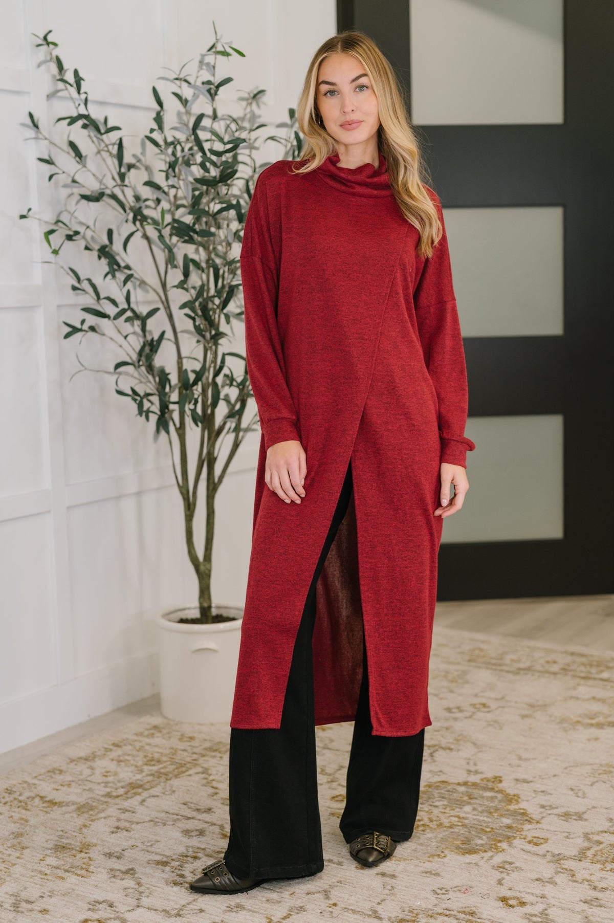 A woman wearing a wine-colored turtleneck tunic with long sleeves and side slits.