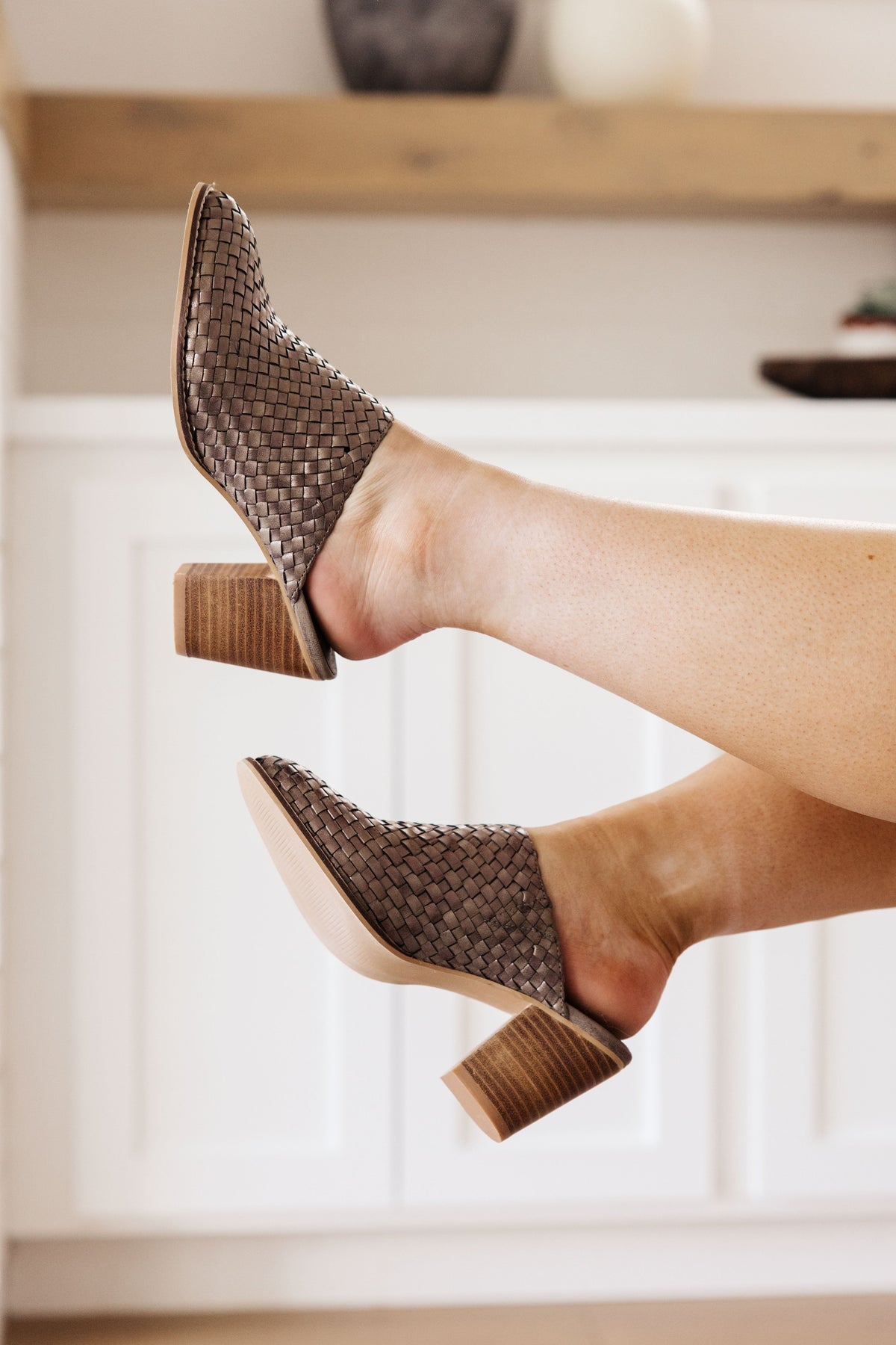 Bronze woven mules with a 3-inch block heel, displayed on feet in a casual setting.