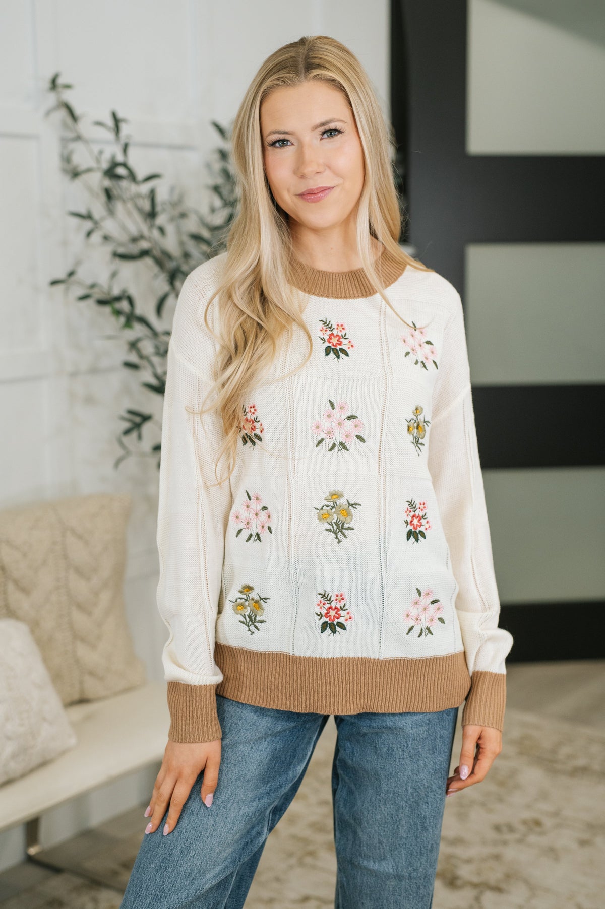 Ivory sweater with embroidered floral designs, ribbed neckline, and hem.