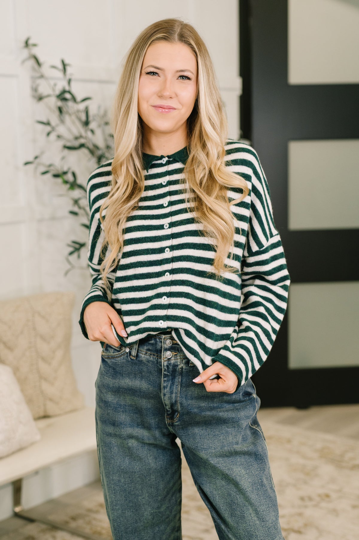 A woman wearing a hunter green and white striped button-down sweater with a collared neckline.