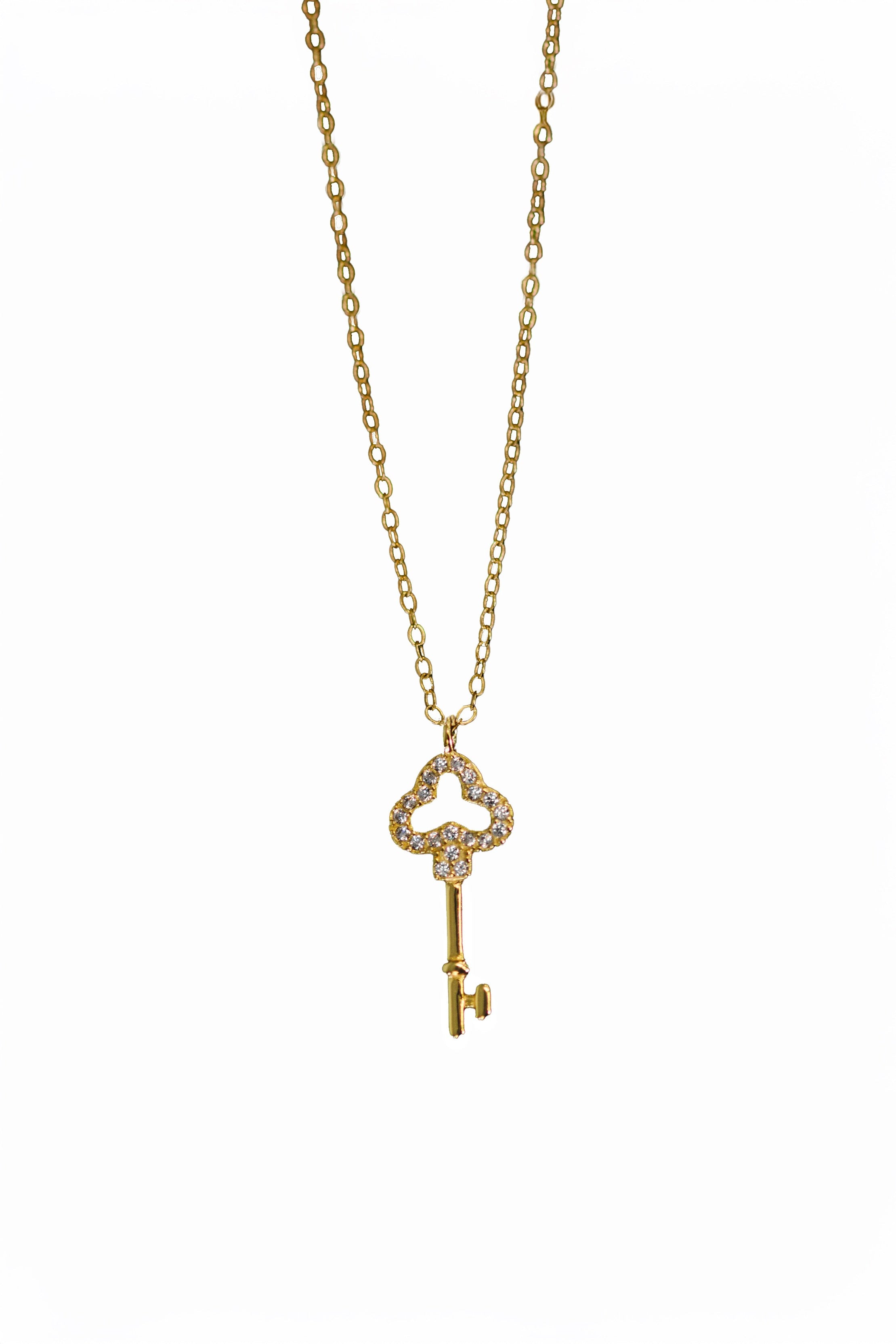 Gold key-shaped pendant necklace on a white background