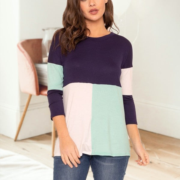 Woman wearing a color-blocked sweater in a minimal indoor setting